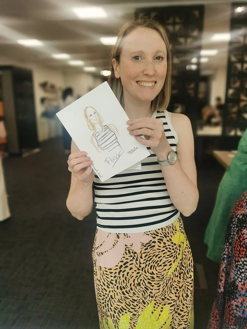 Short, blonde-haired woman holding up a quick portrait by Siya Liu at the NatWest Event. 