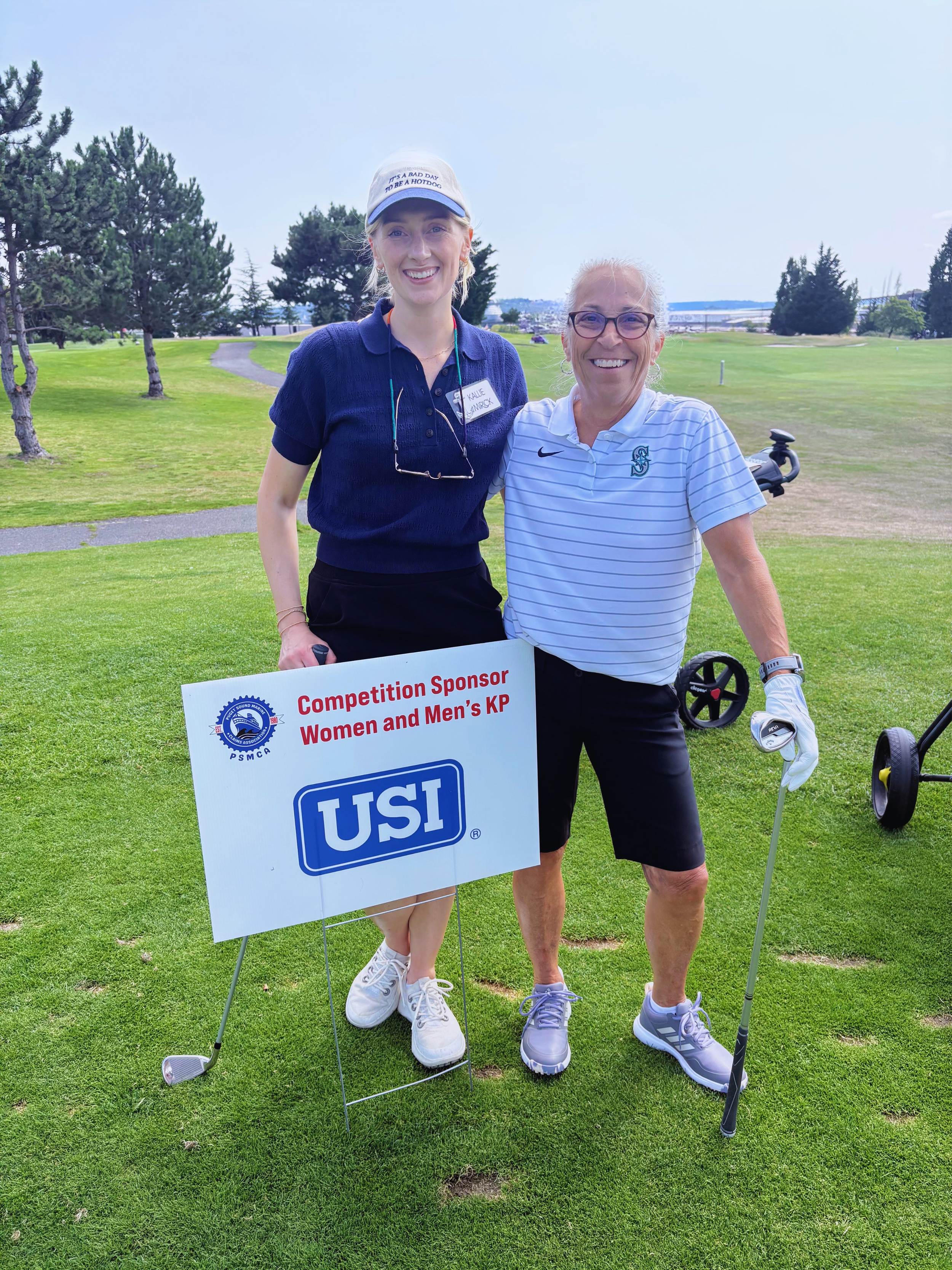 Kallie Mirick & Sue Goheen smile by the USI Competition Hole Sign.