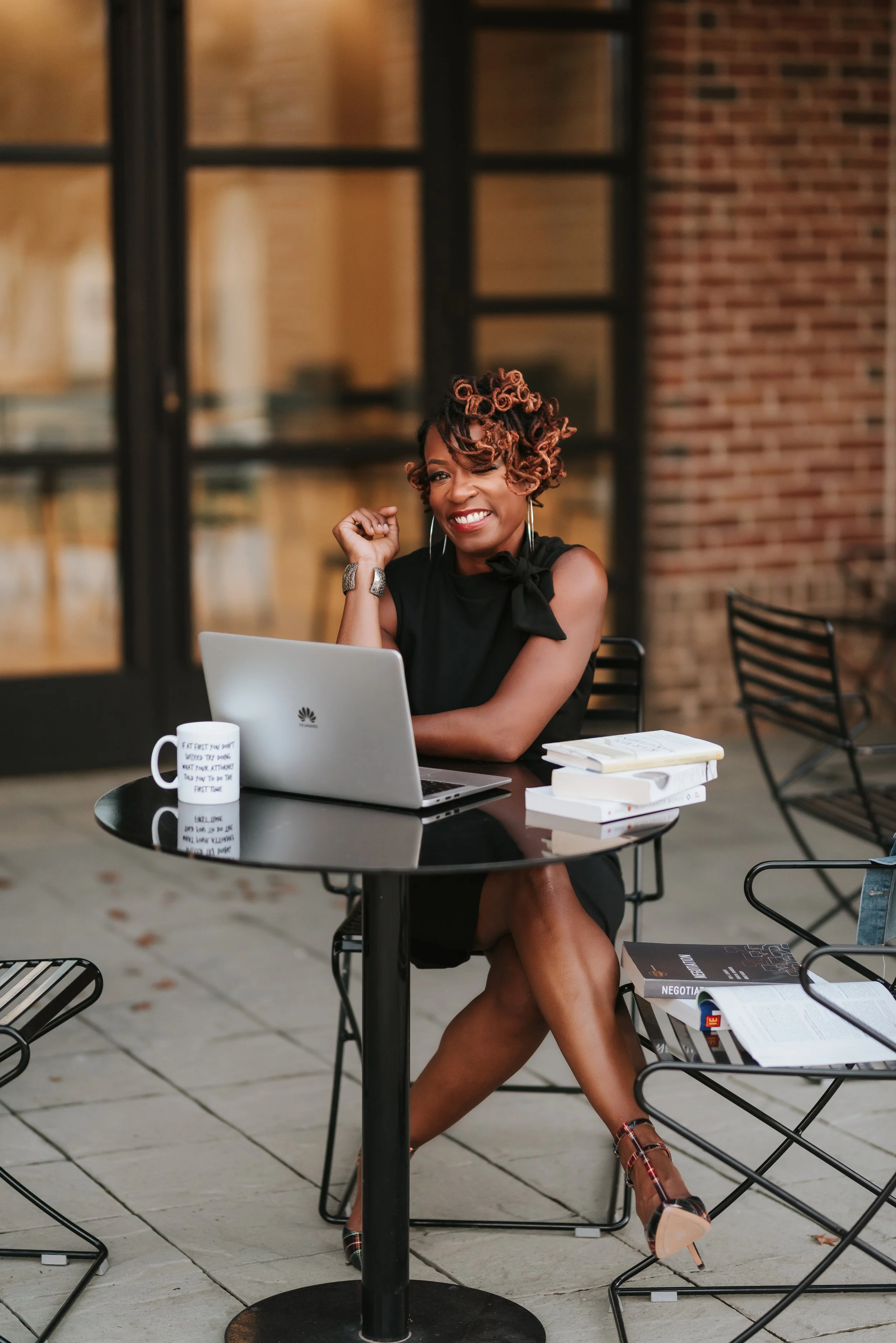 Sonia sitting at table smiling with laptop