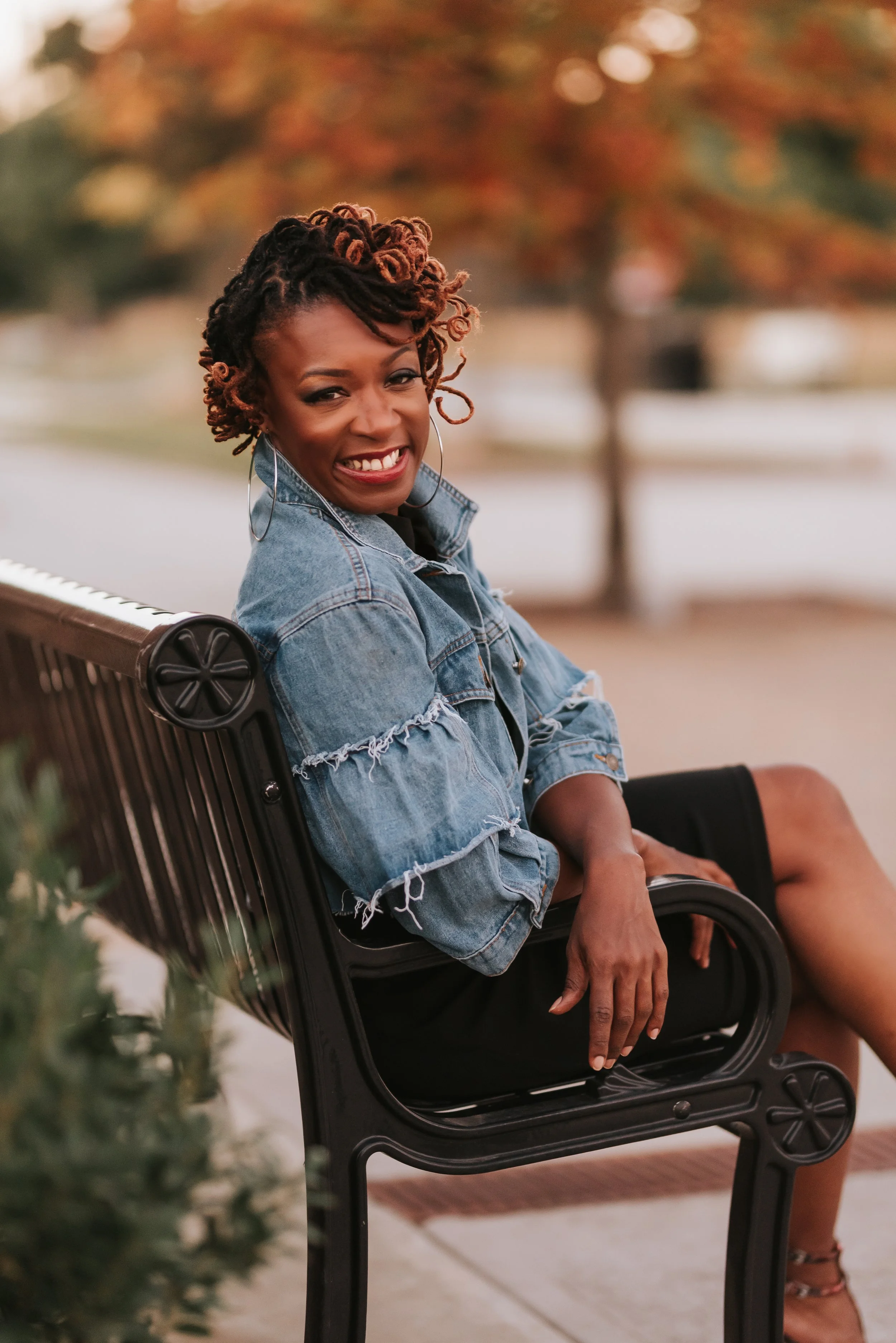 Sonia Toson on a bench smiling in a jean jacket