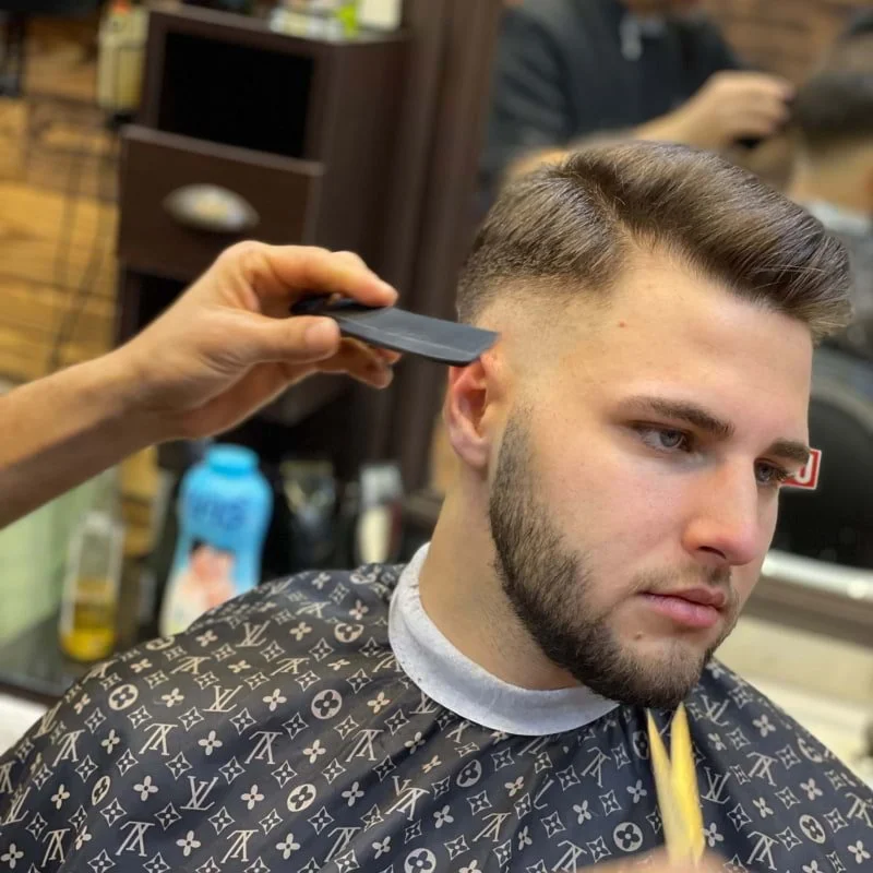 Man getting a haircut with fade hairstyle at barbershop