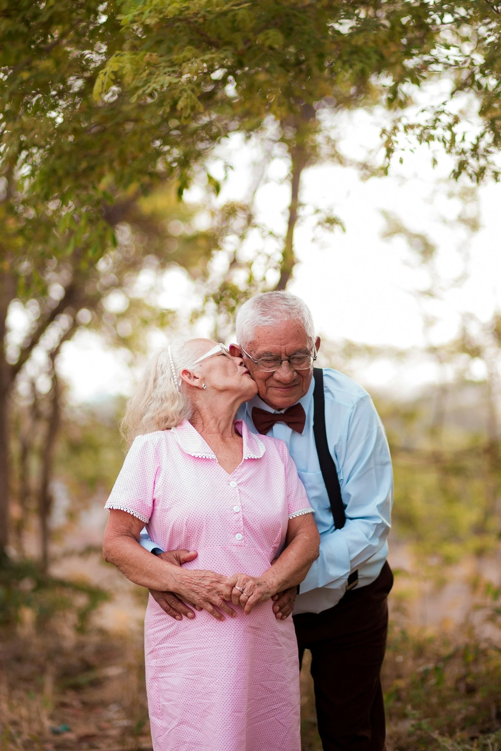 elderly couple hugging with woman giving man a kiss