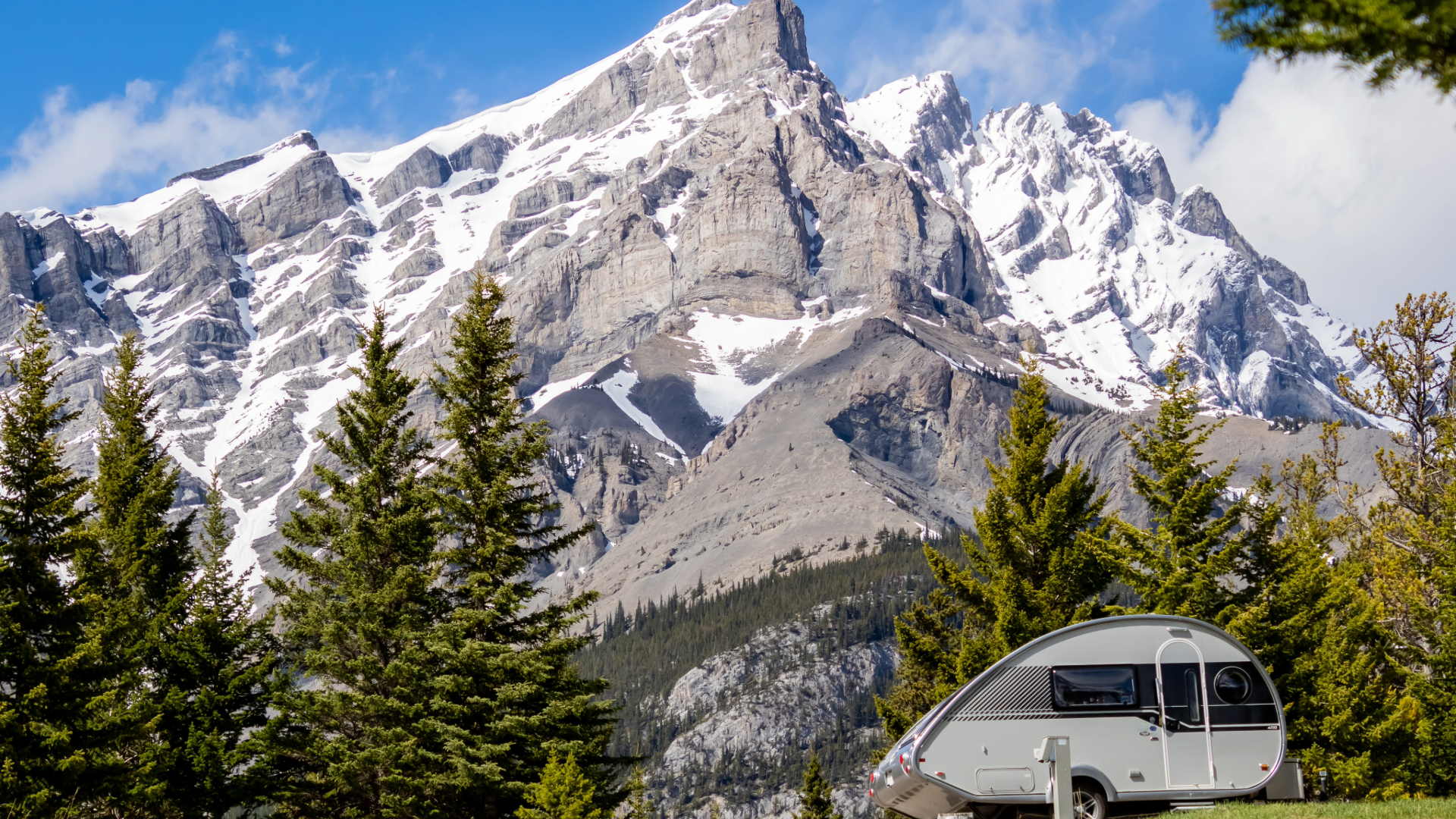 teardrop trailer parked in front of snow covered mountain