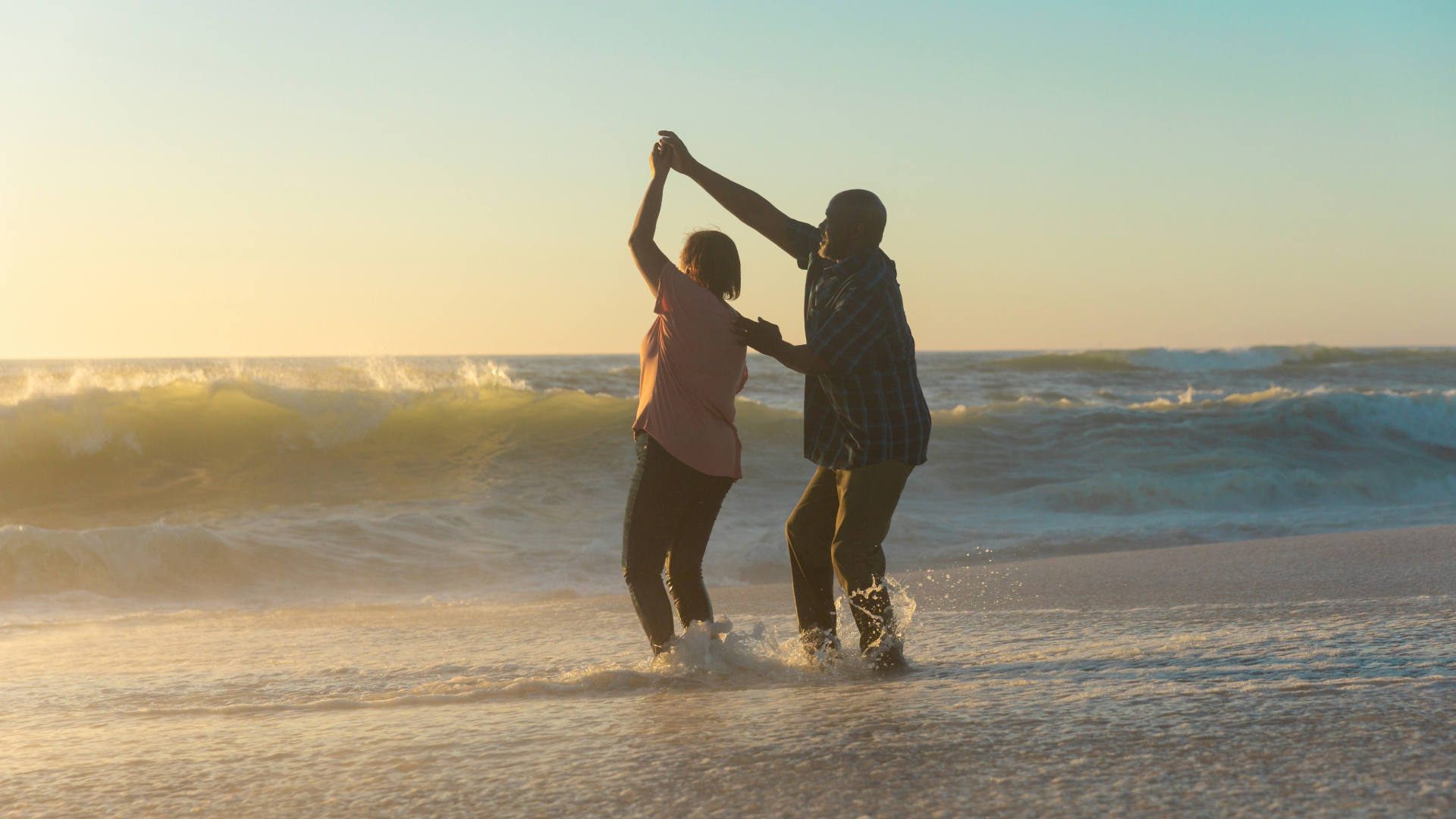 couple dancing at foot of ocean at sunset