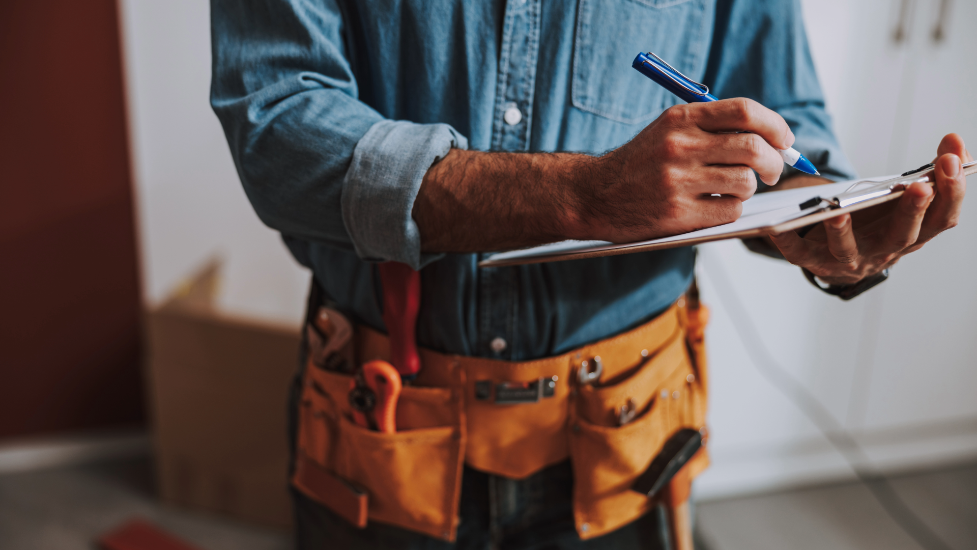 contractor with tool belt writing up an invoice