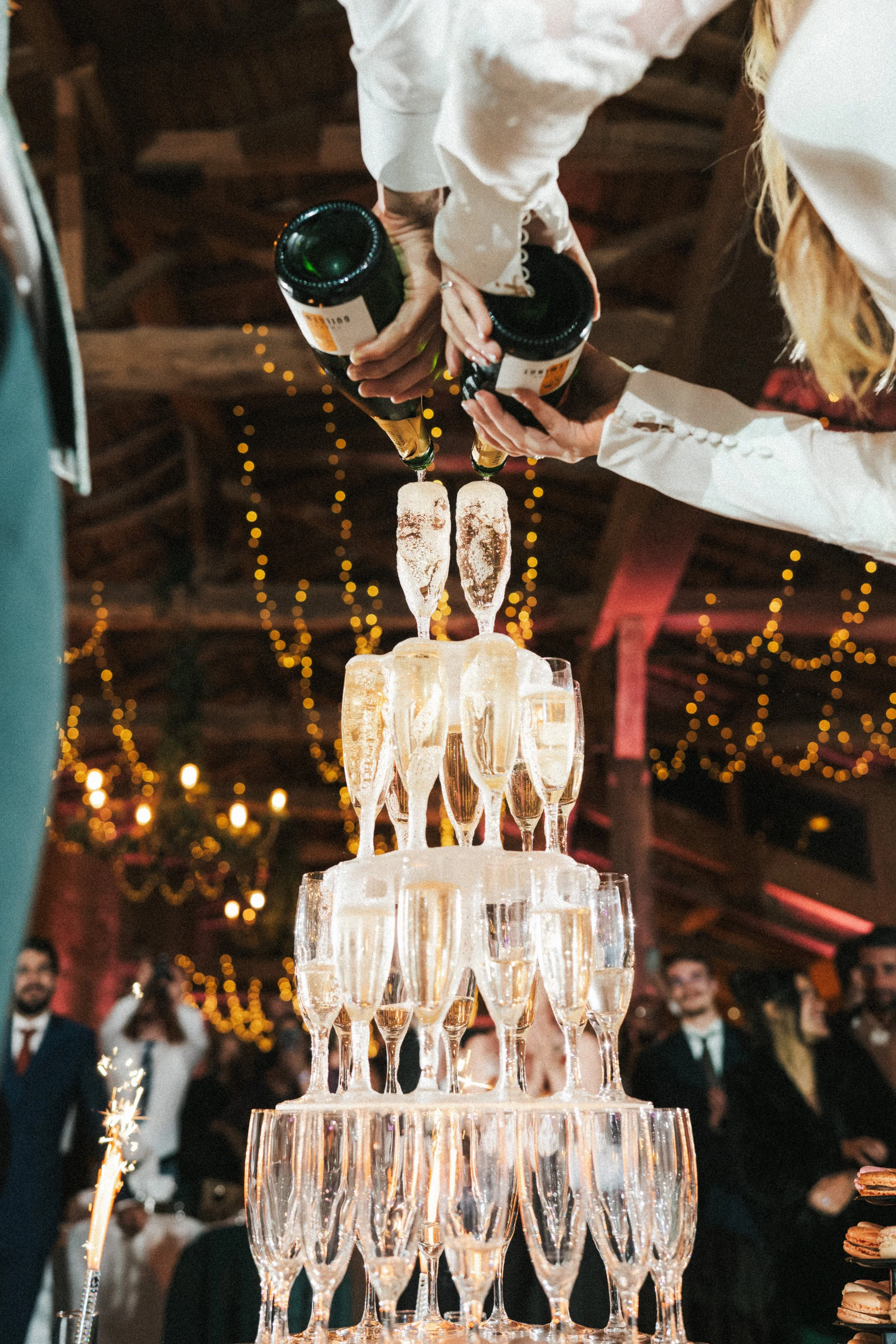 Groupe de personnes décorant un gâteau en forme de pyramide de flutes à champagne lors d'une célébration
