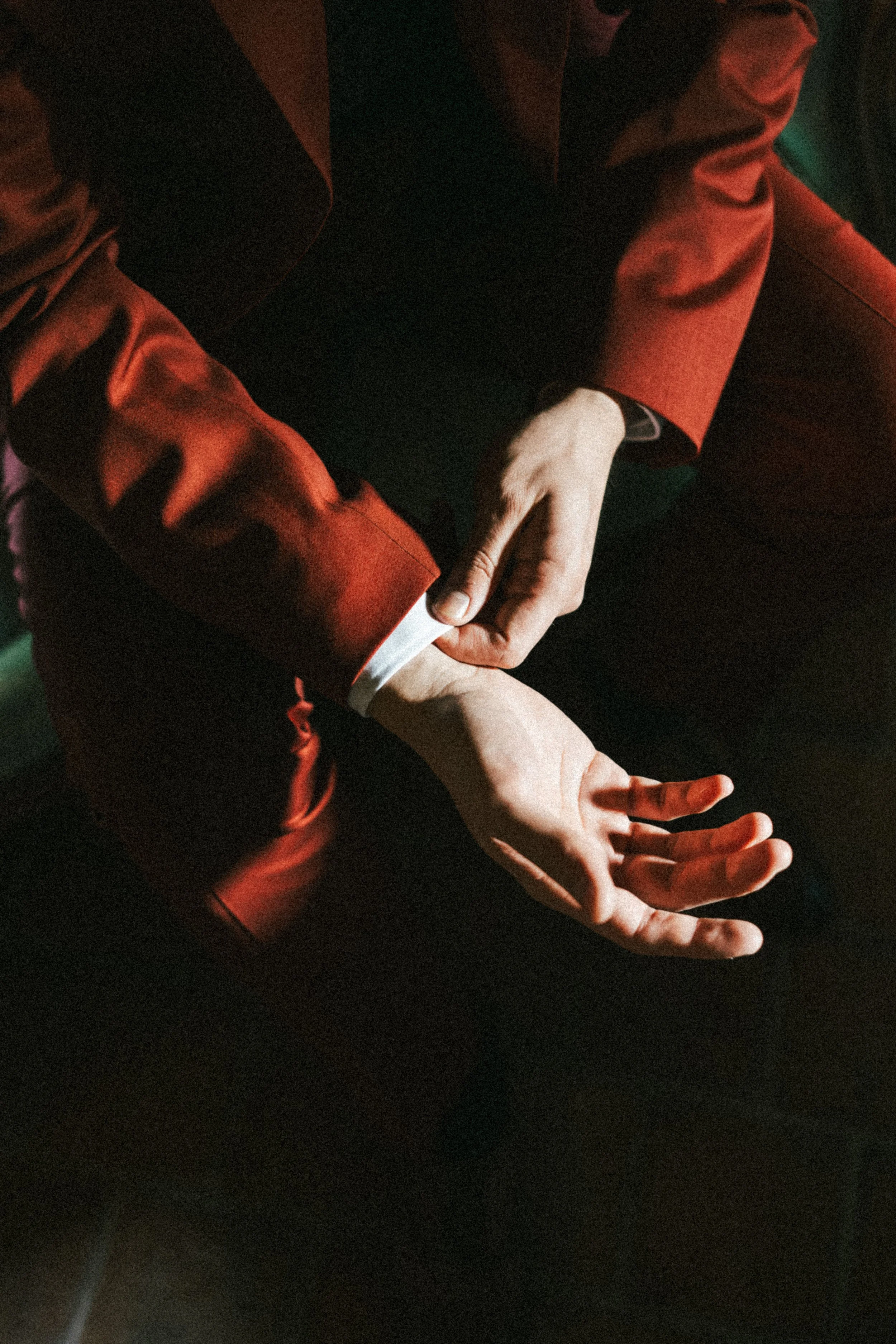 Un homme en costume rouge ajuste le poignet de son costume.