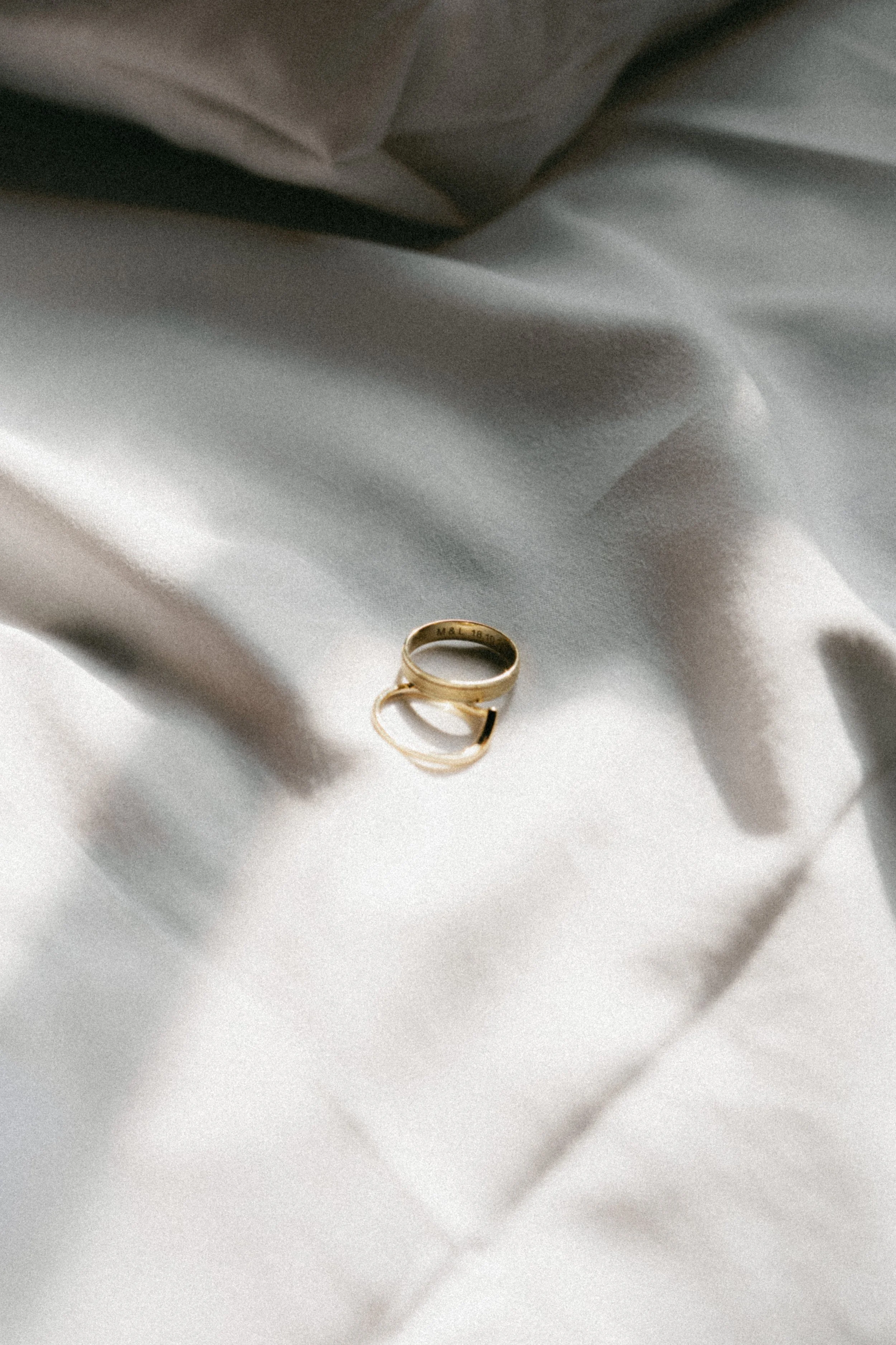 Une bague dorée posée sur un tissu blanc avec des ombres douces.
