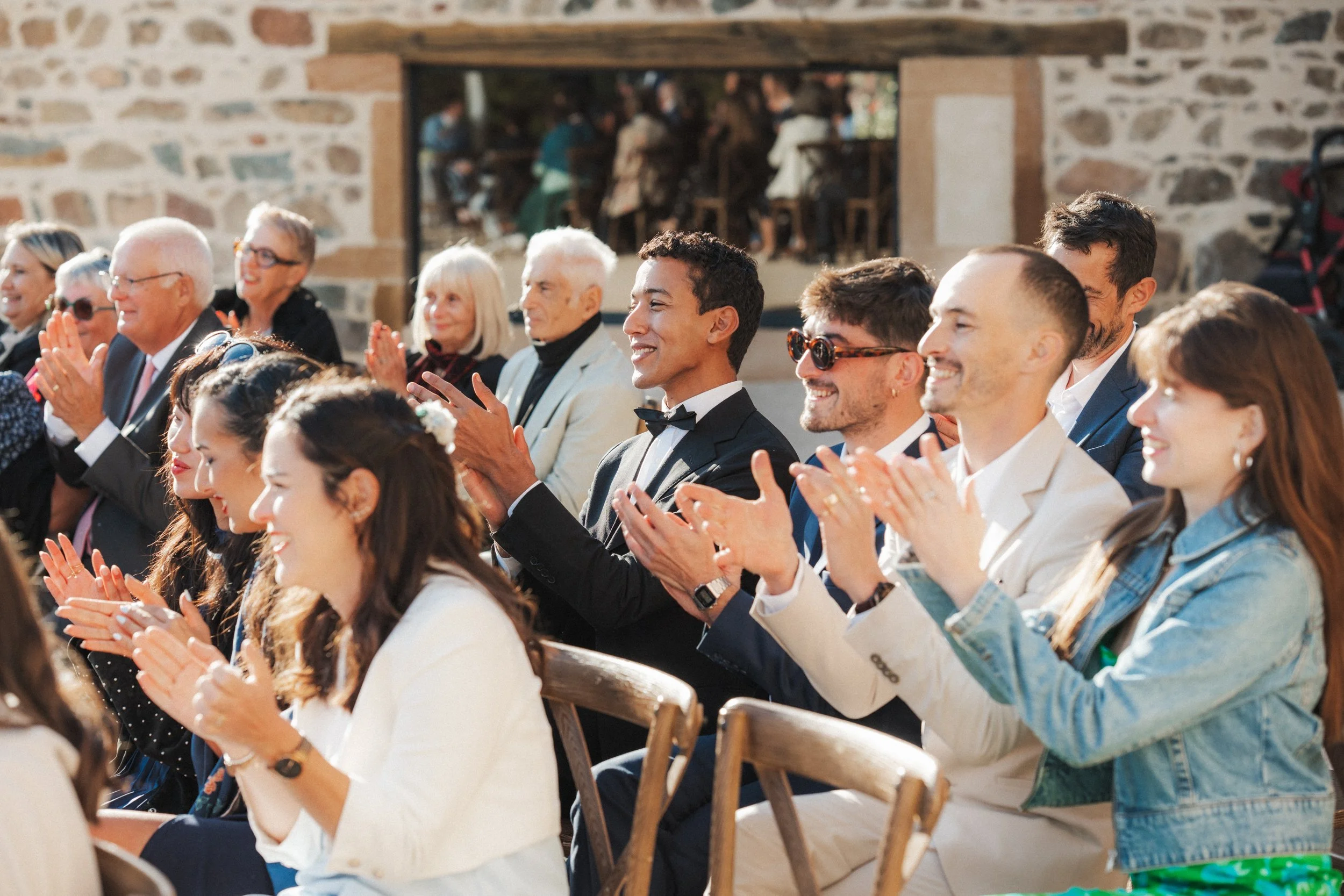 Groupe de personnes assises et applaudissant à un événement en plein air