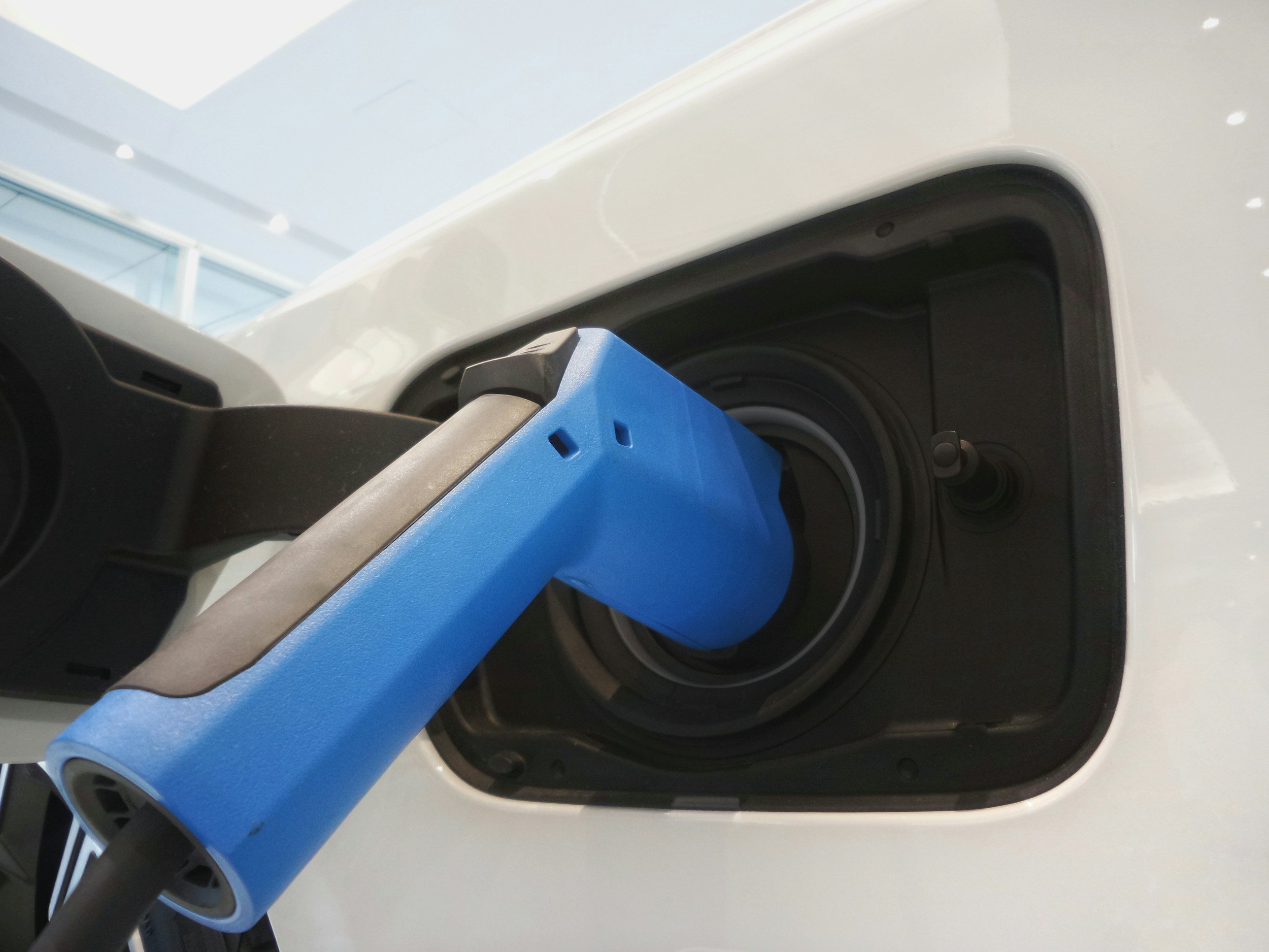 Close-up of an electric vehicle charging port with a blue charging connector inserted.