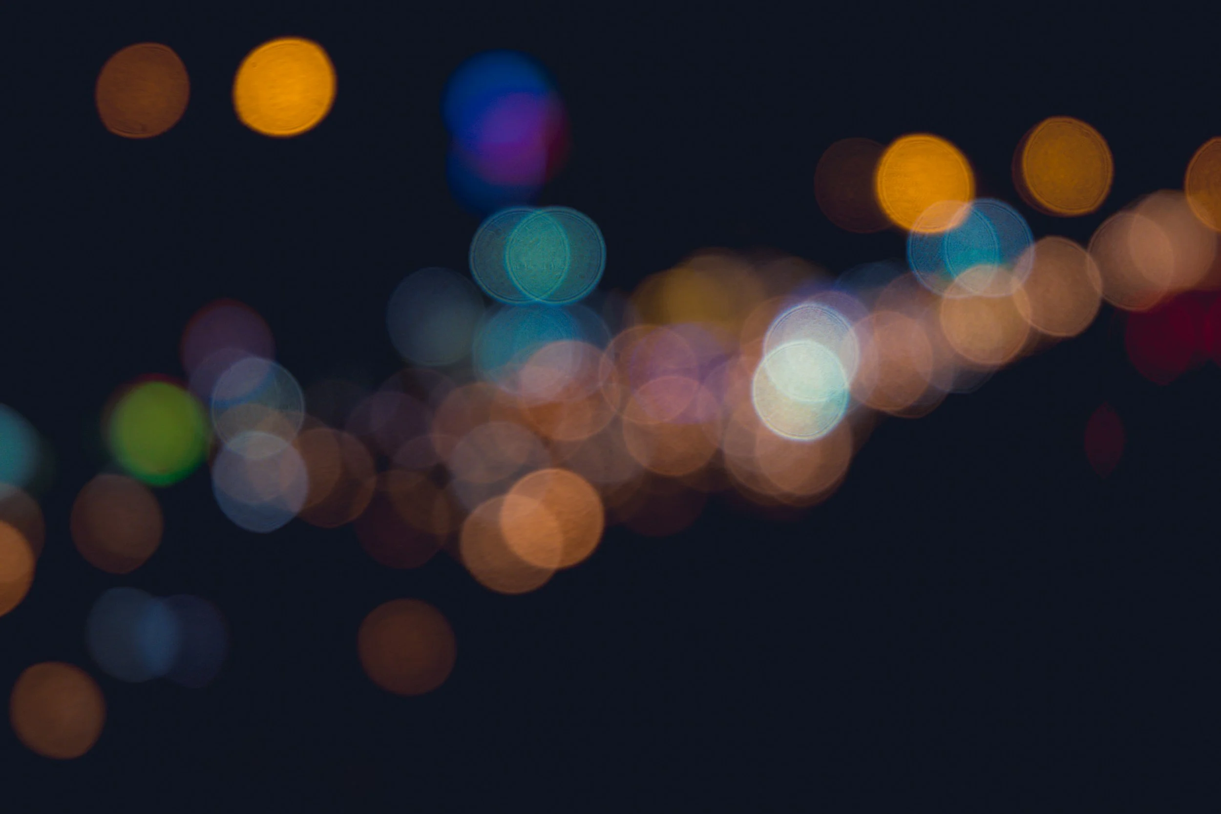 Blurred city streetlights at night creating bokeh effect with circles of various colors.