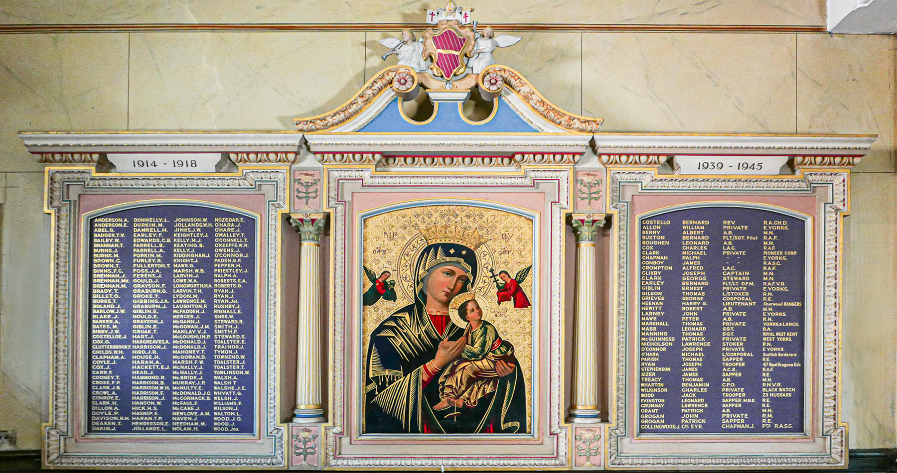 A religious memorial display featuring an icon of the Virgin Mary holding baby Jesus, flanked by angels, with decorative columns and plaques listing names and dates of service.