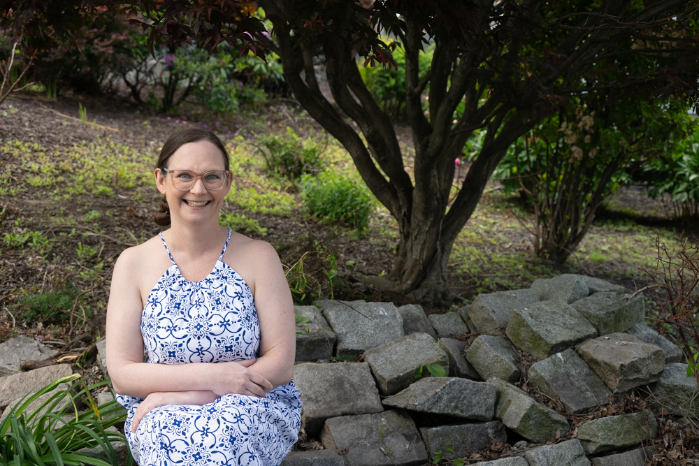 Sarah Gaw sits on rocks in a garden