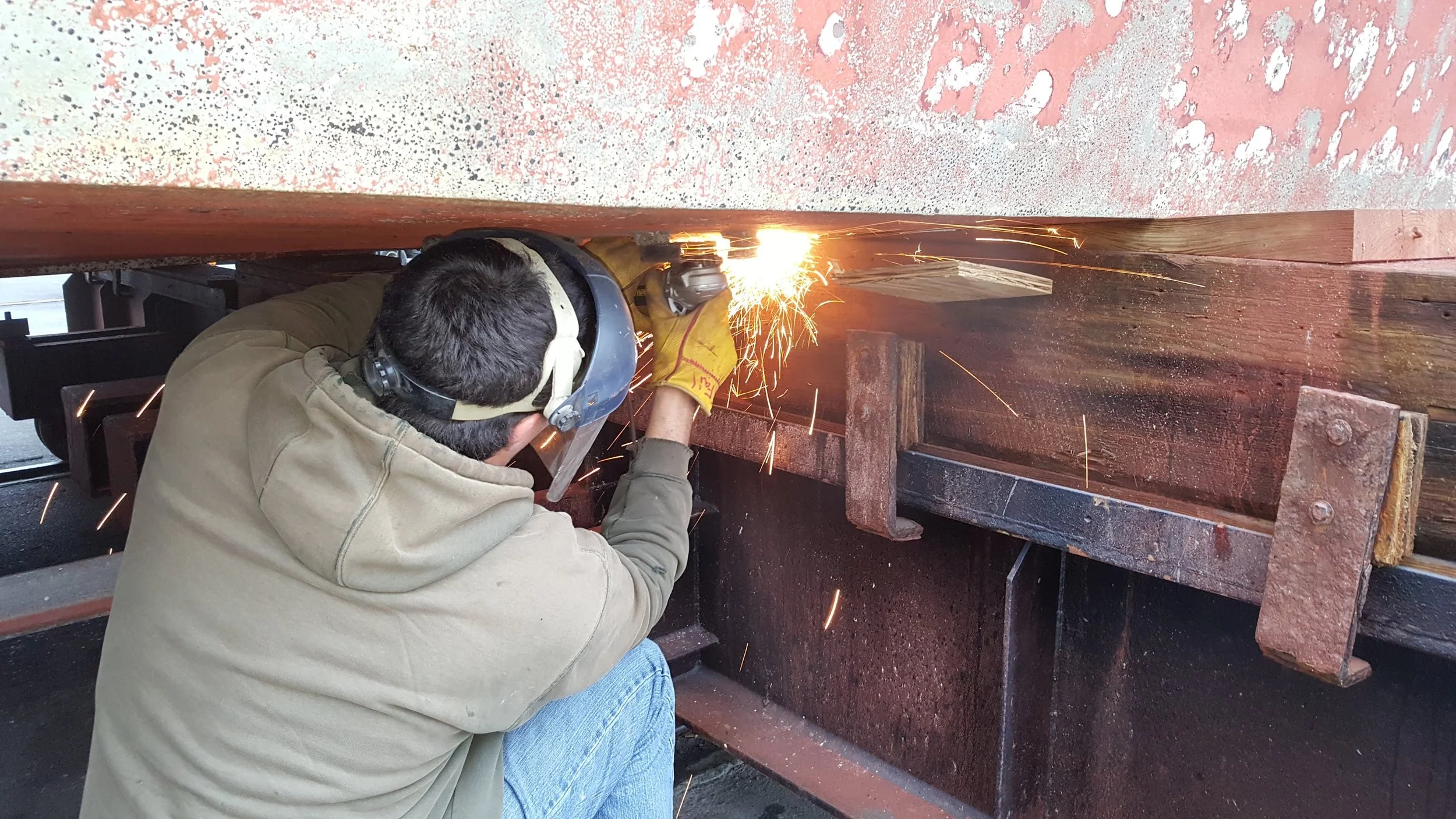 Metal surface preparation on commercial tug hull underside during drydock period — quality oversight by KEY Marine Advisors