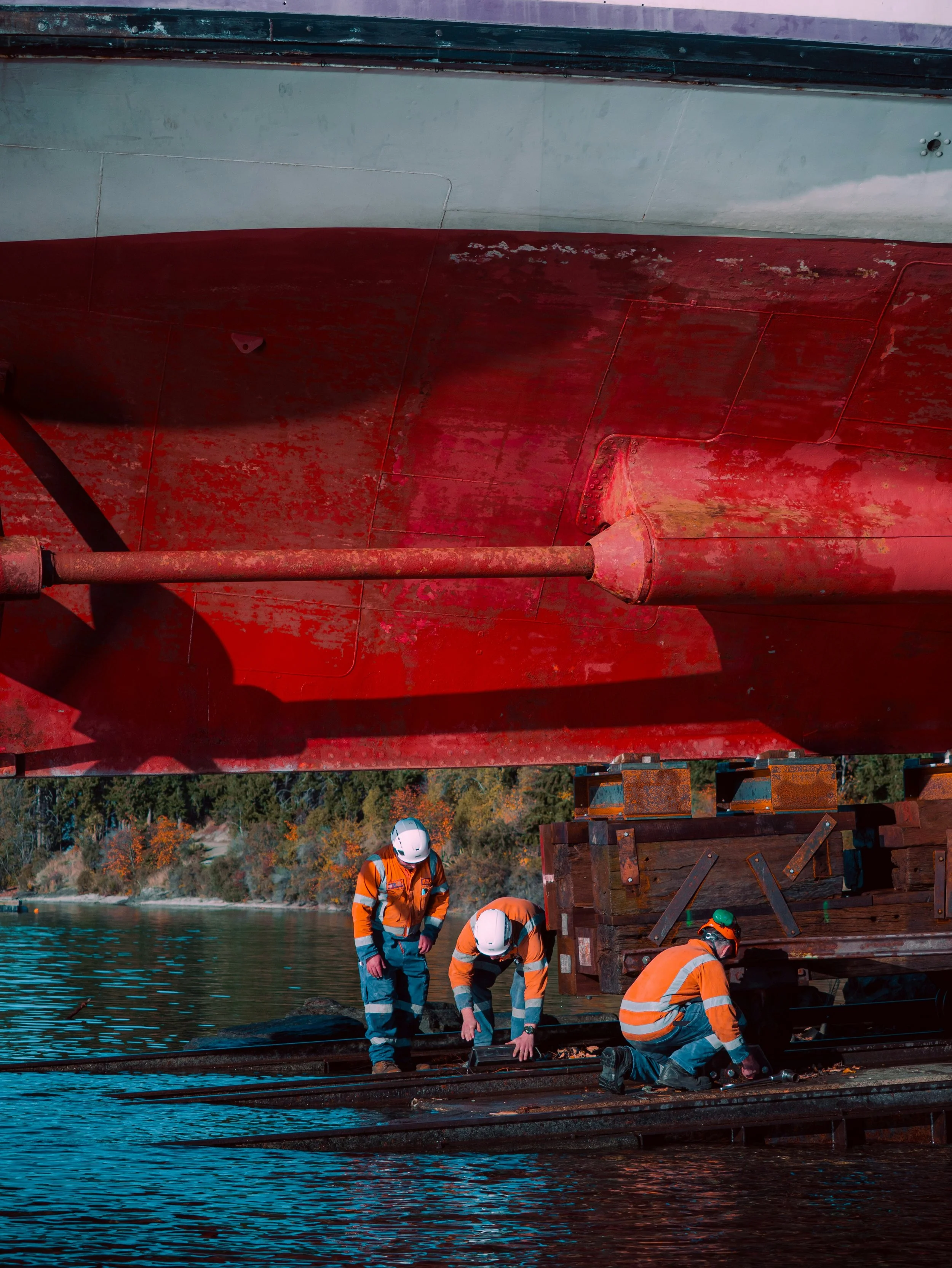 Shipyard workers in safety gear during active vessel haul-out for running gear repairs at Singapore commecial ship repair facility.