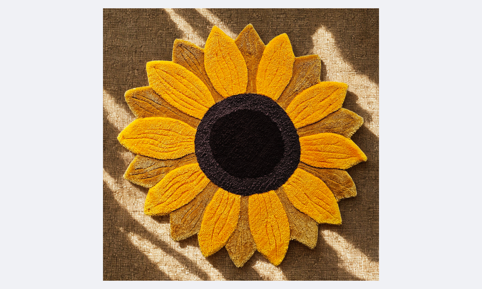 A decorative sunflower made of yellow and brown fabric with a black center, placed on a textured brown surface with light streaks.