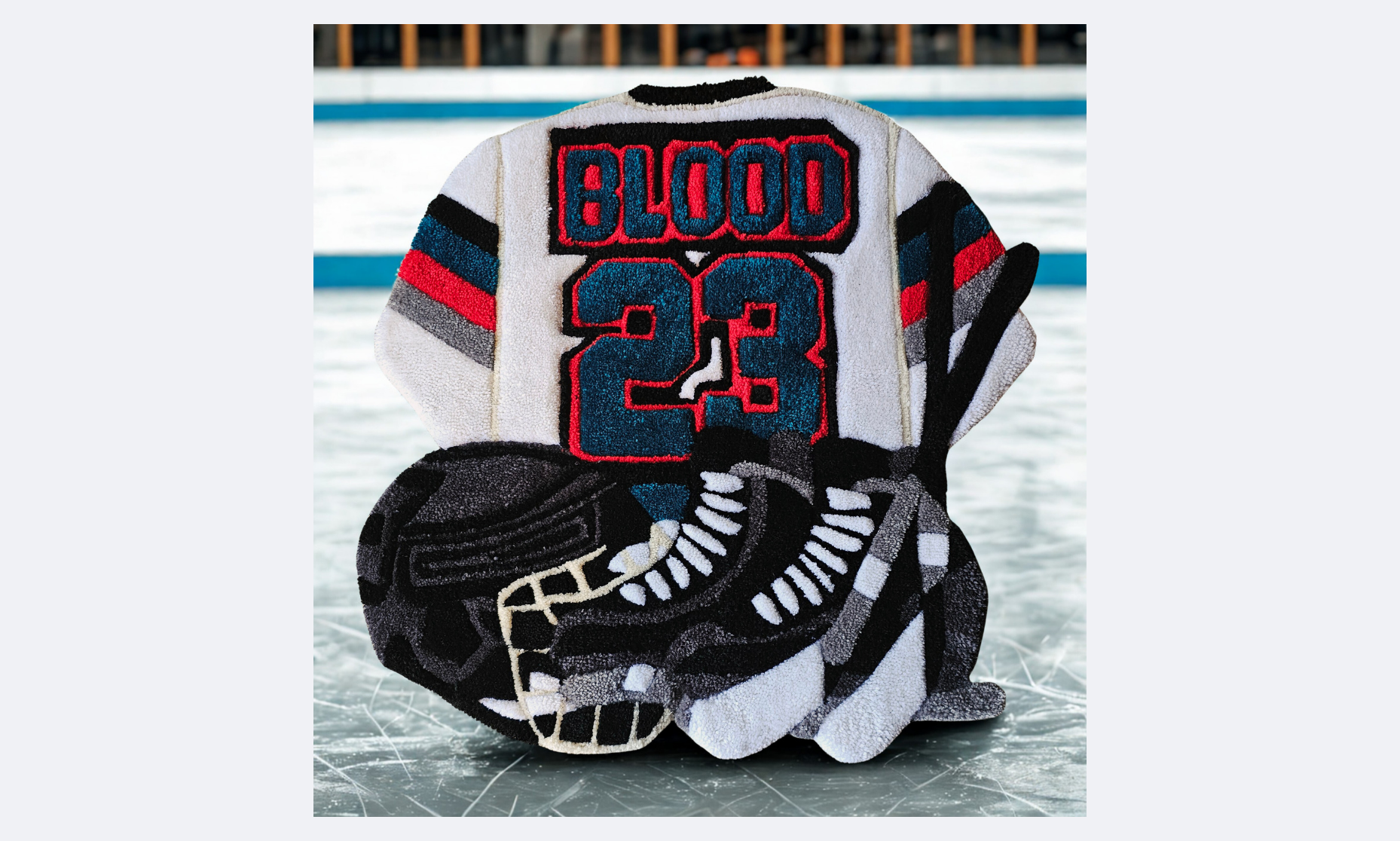 A hockey towel with a design inspired by the Detroit Red Wings, featuring a hockey helmet, a hockey stick, and a hockey puck, set on an ice rink.