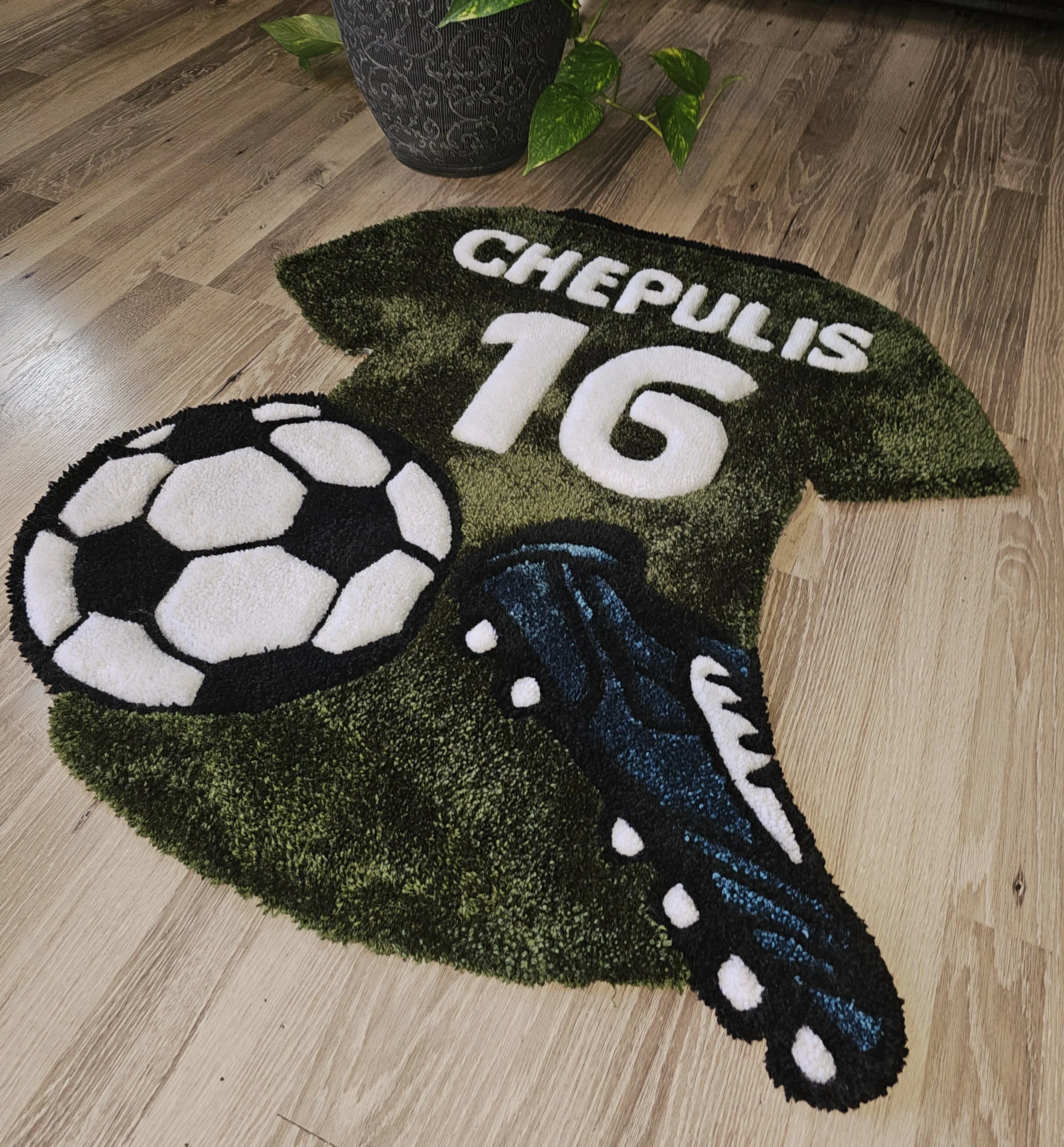A football-themed rug with a soccer ball and a blue butterfly, inscribed with the words "CHEPULIS 16."