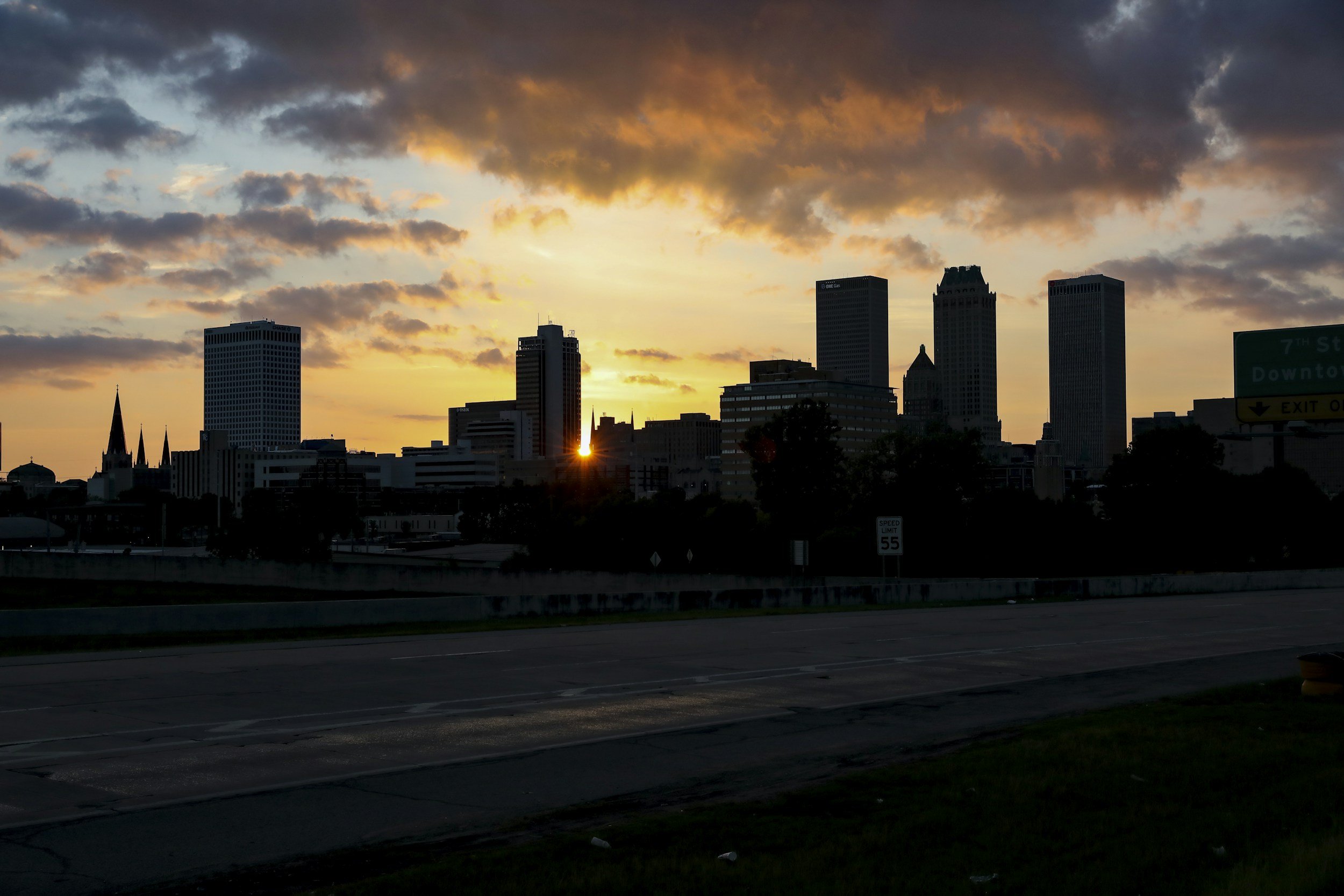 City skyline at sunset with tall buildings and a partly cloudy sky.