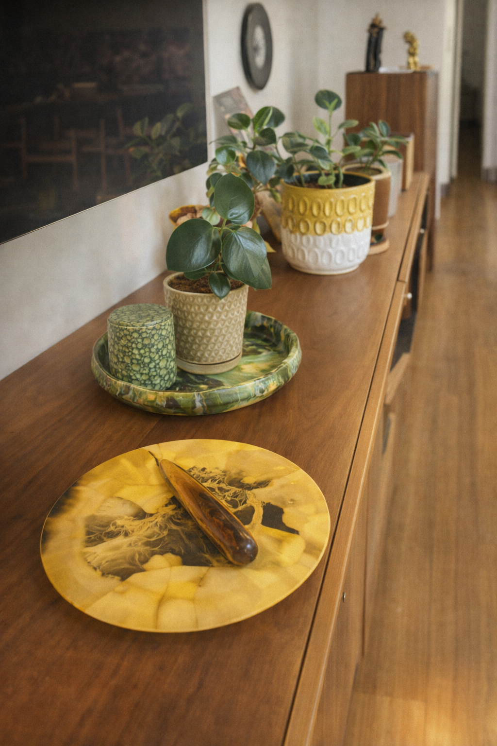 Decorative items on a wooden sideboard, including potted plants, candles, and a decorative tray and plate.