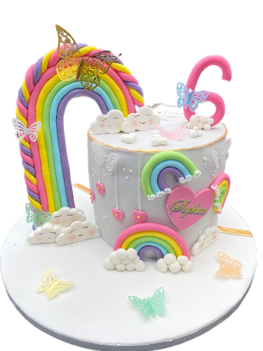 Colorful birthday cake with rainbows, clouds, butterflies, and a pink number six candle.