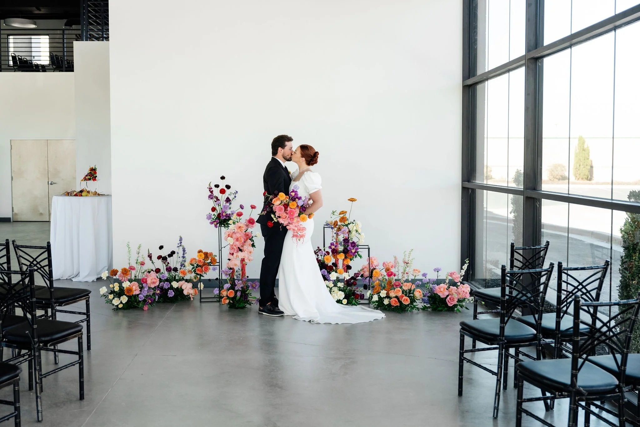 A bride and groom kiss in our Enchanted Hall in front of a ceremony centerpiece and seating