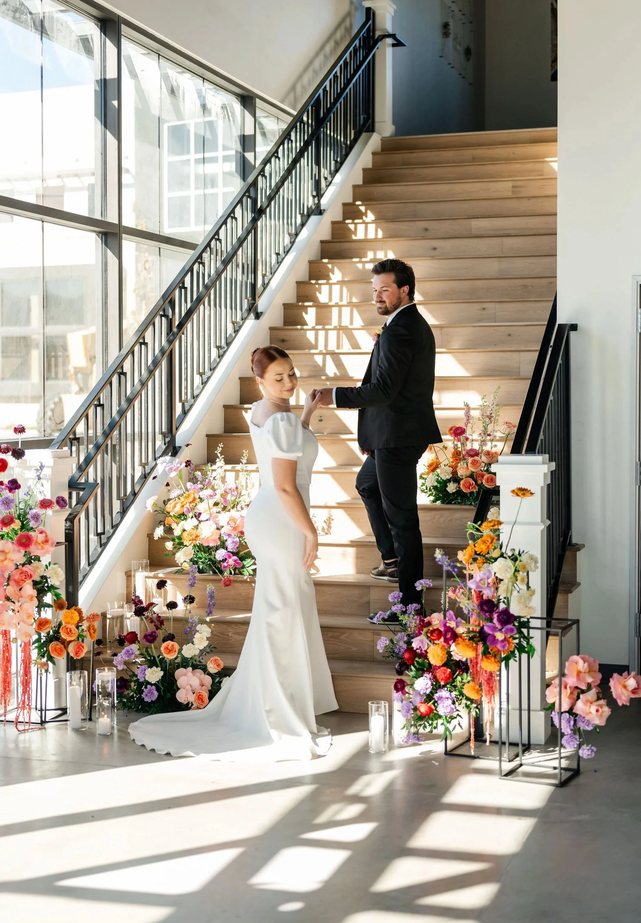 Newlywed couple posing on a grand staircase surrounded by vibrant floral arrangements at our premier Utah wedding venue