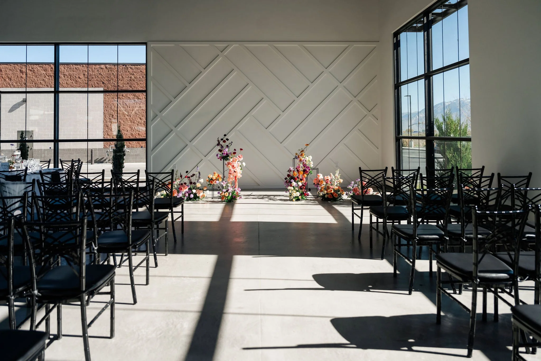 A wider view of the aisle of ceremony seating with a colorful floral centerpiece at the head in our Enchanted Hall