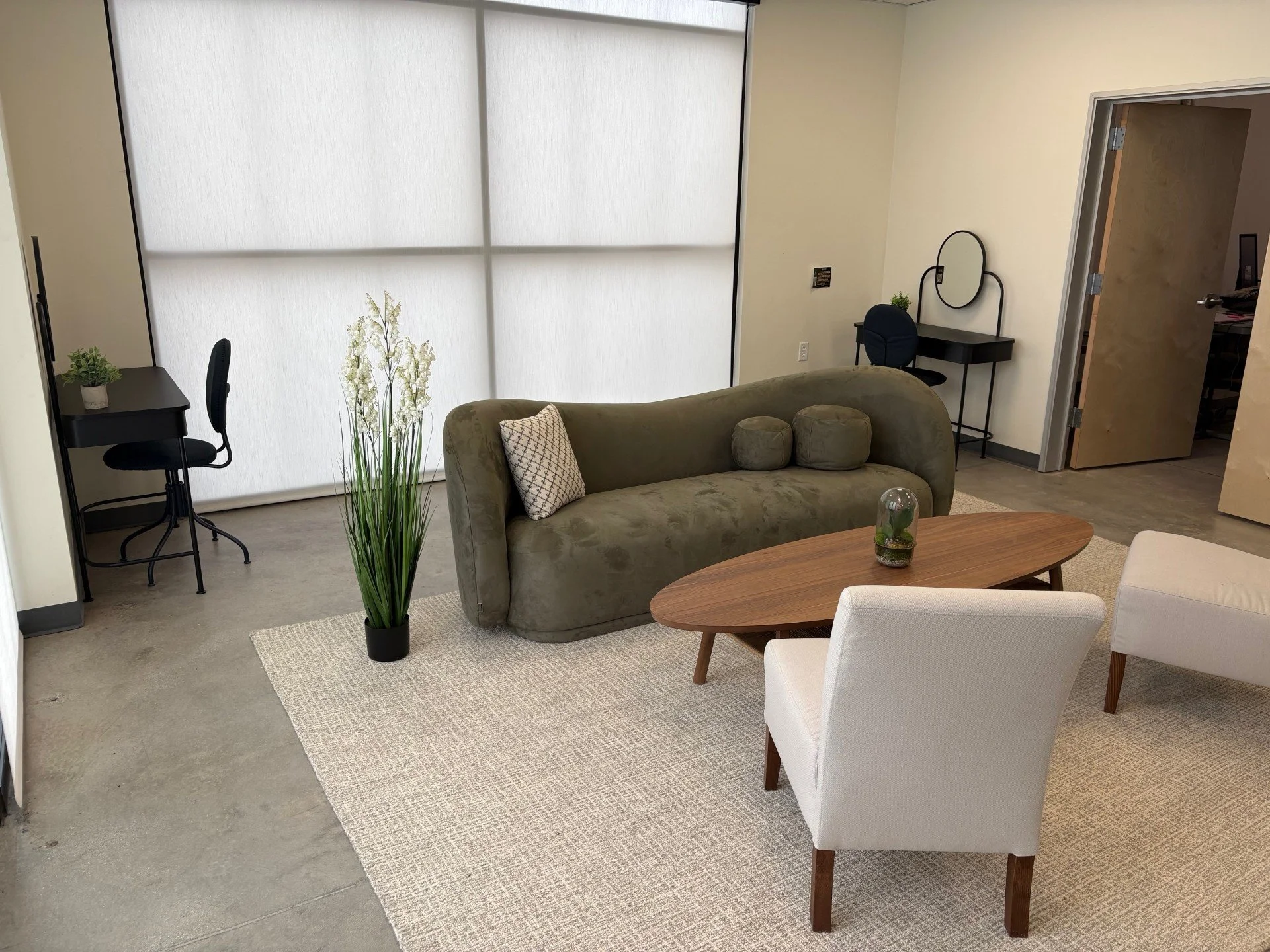 Our getting ready room with green elegant modern couch and beige chairs, vanities, and light floral arrangement makes for a private and cozy space to prepare for the event