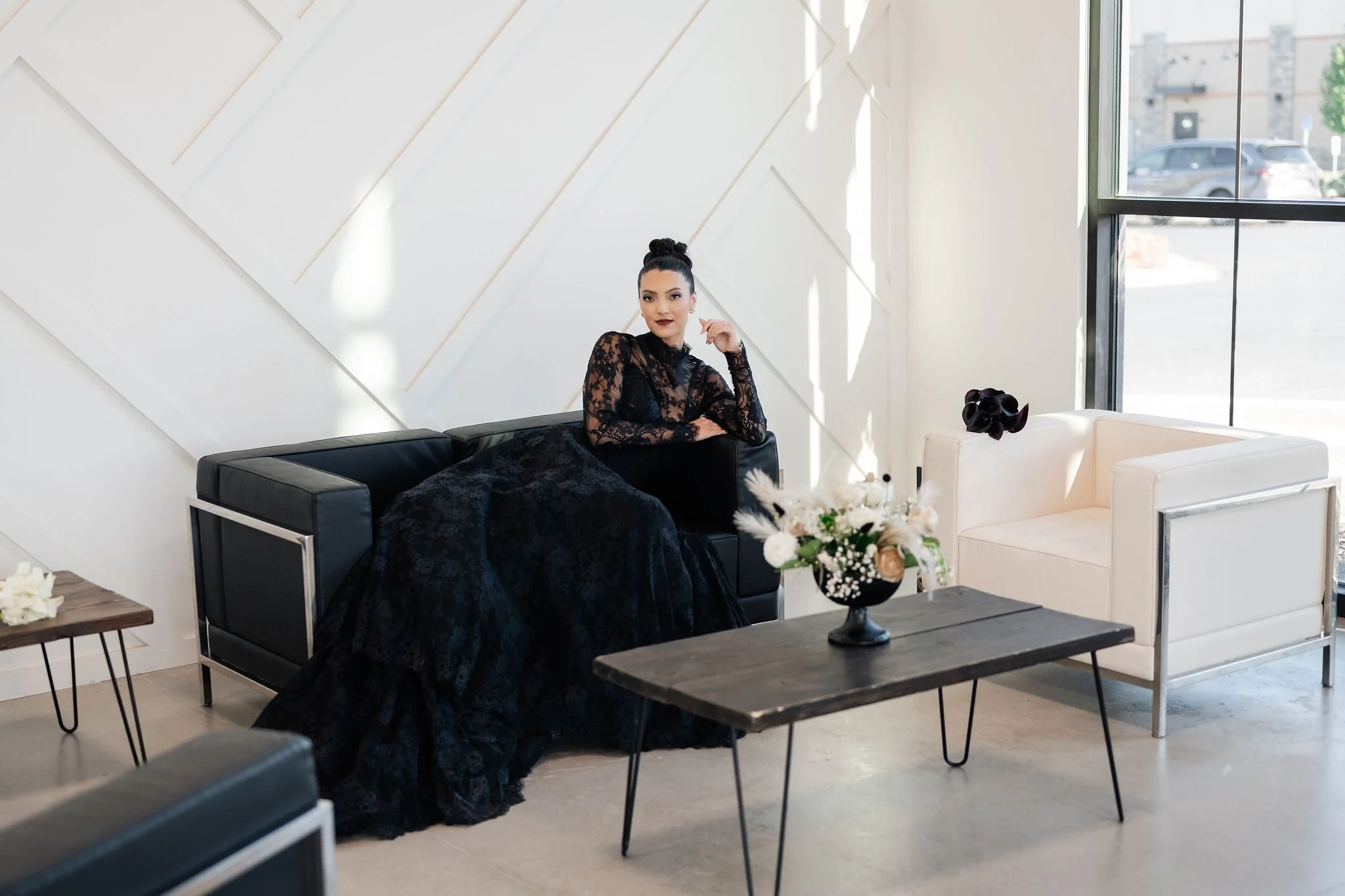 Bride in a dark wedding gown seated in modern furniture in our Herriman event venue