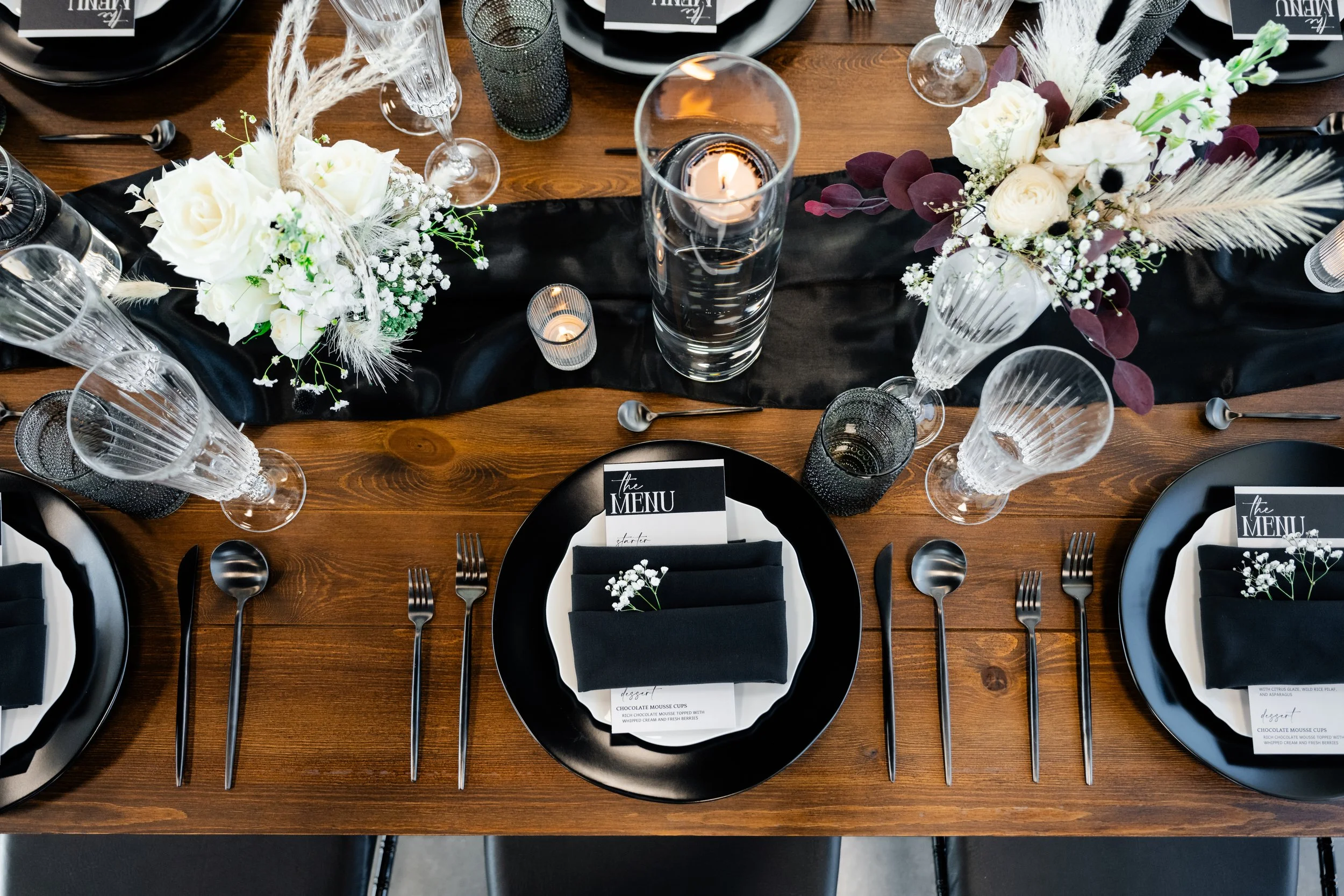 Table settings of a wedding reception with plates, utensils, and glassware, at Herriman wedding venue, Enchanted Events Center