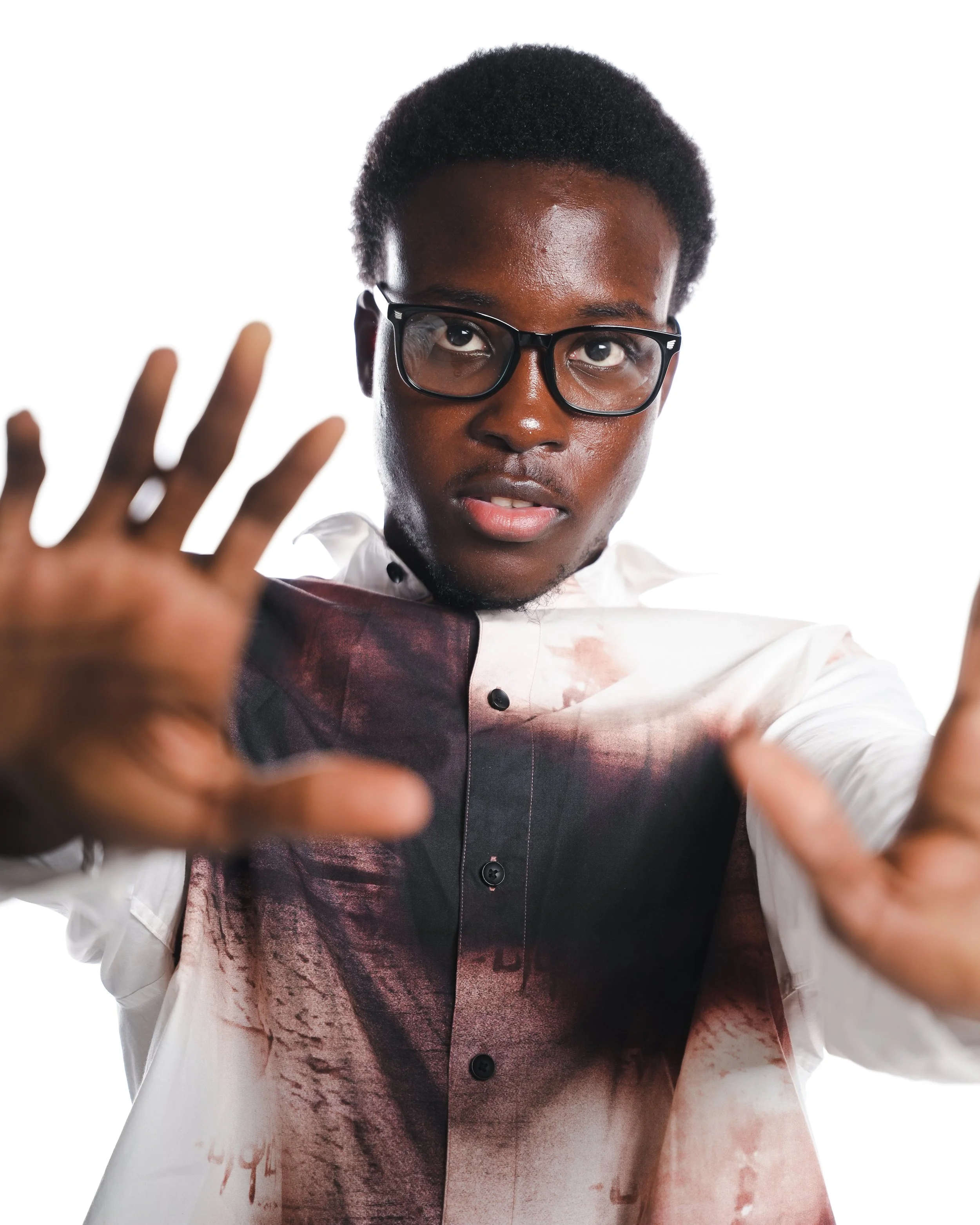 Young man wearing glasses and a white shirt reaching towards the camera, with a surprised or intense expression, against a plain white background.