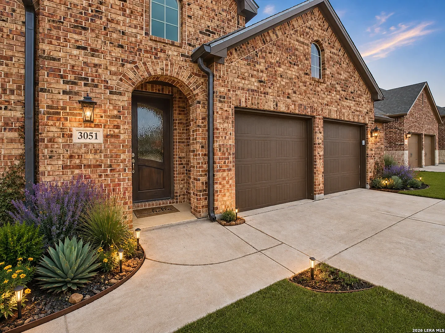 Brick house with a black front door, two-car garage, and landscaped front yard with pathway lights at 3051 Blenheim Park, Bulverde, Texas.
