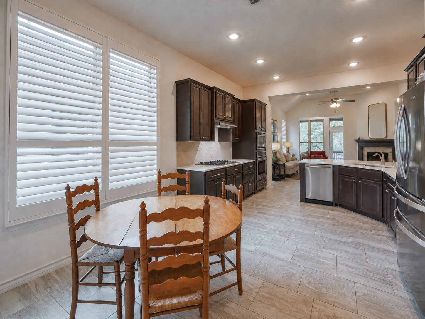 Open-concept kitchen and living area with dark wood cabinets, stainless steel appliances of 3051 Blenheim Park, Bulverde, Texas.