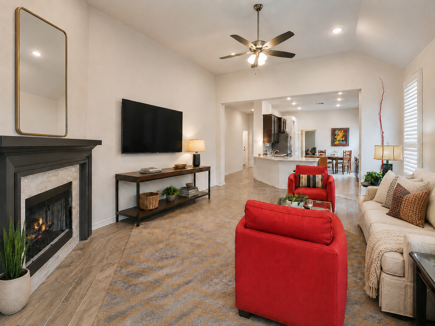 Living room with beige sofa, red armchair, fireplace, television, and a glass coffee table of 3051 Blenheim Park, Bulverde, Texas.
