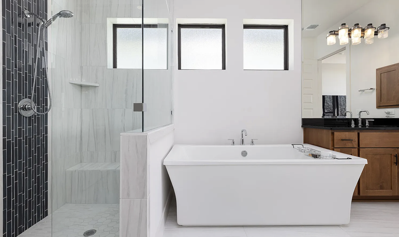 Modern bathroom with a glass-enclosed shower, a white bathtub, wooden vanity with black countertop, and three small frosted windows