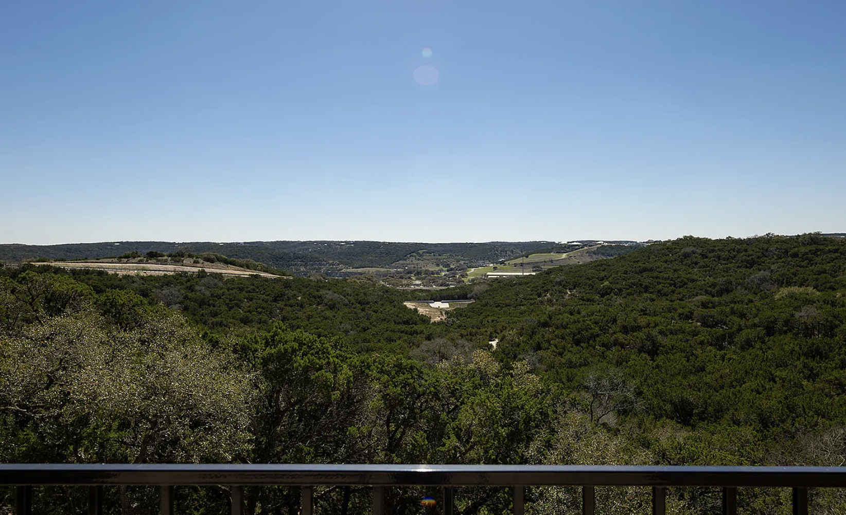 A panoramic view of a green forested landscape with hills under a clear blue sky.