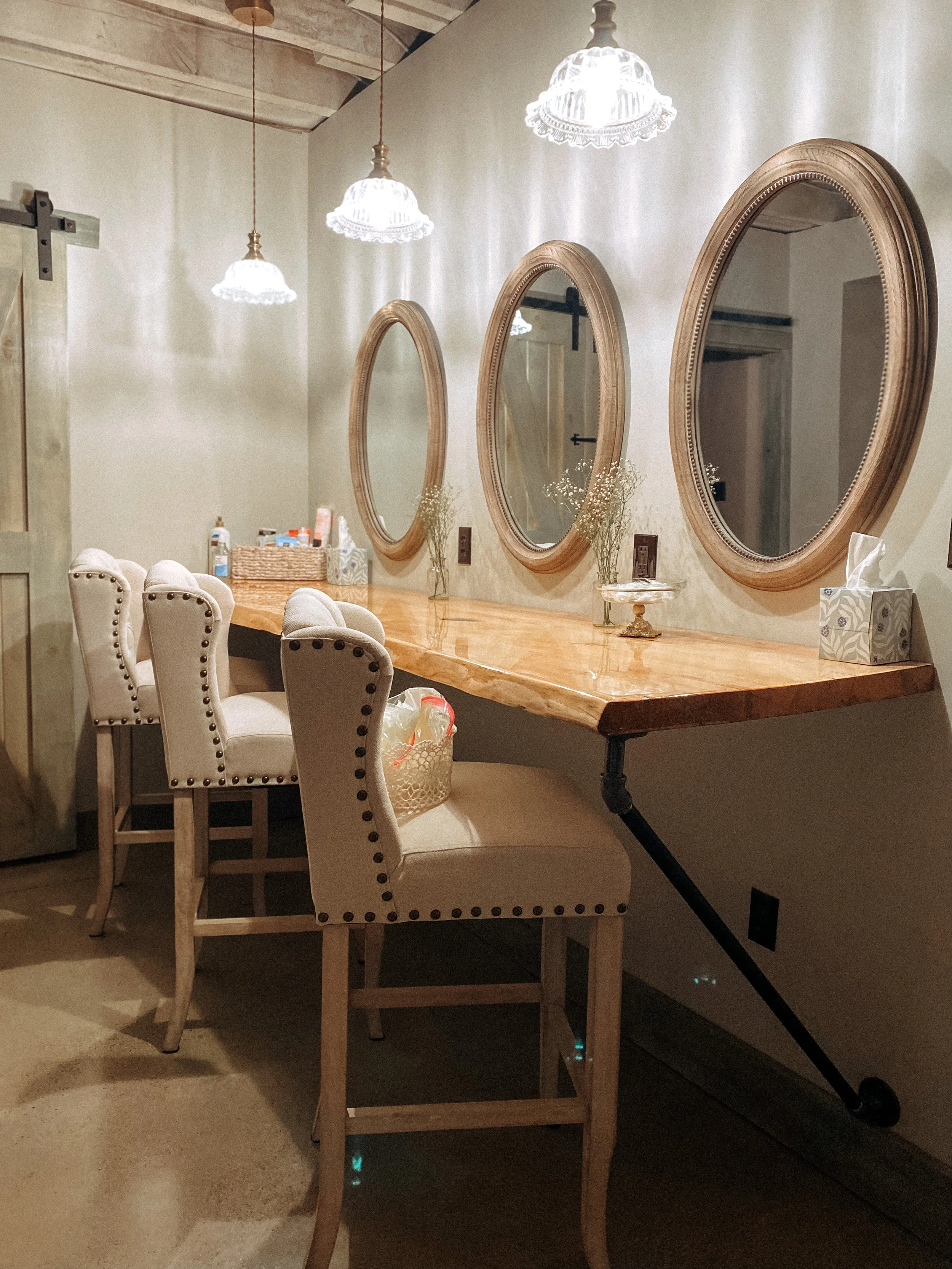Three round mirrors hanging on a wall above a wooden counter, with chairs and decorative items in the room.
