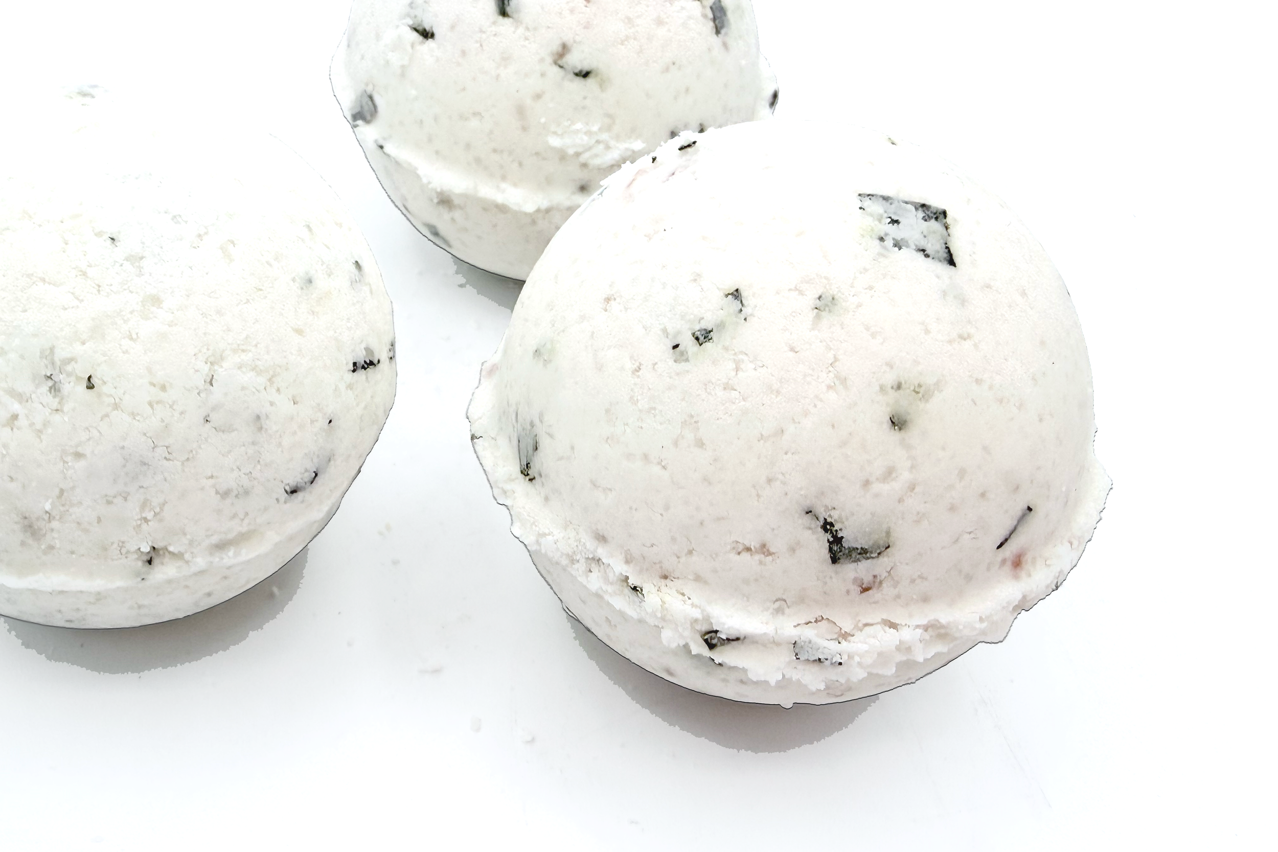 Three scoops of cookies and cream ice cream with chocolate cookie pieces on a white surface.
