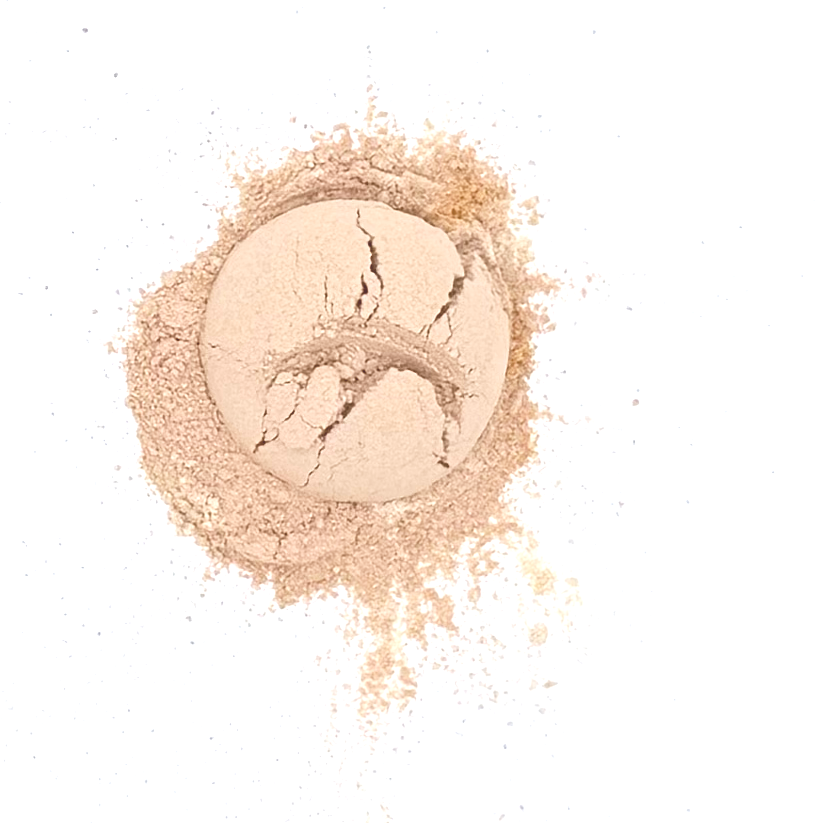 Cracked light-colored powder in a circle with loose powder scattered around on a white background.