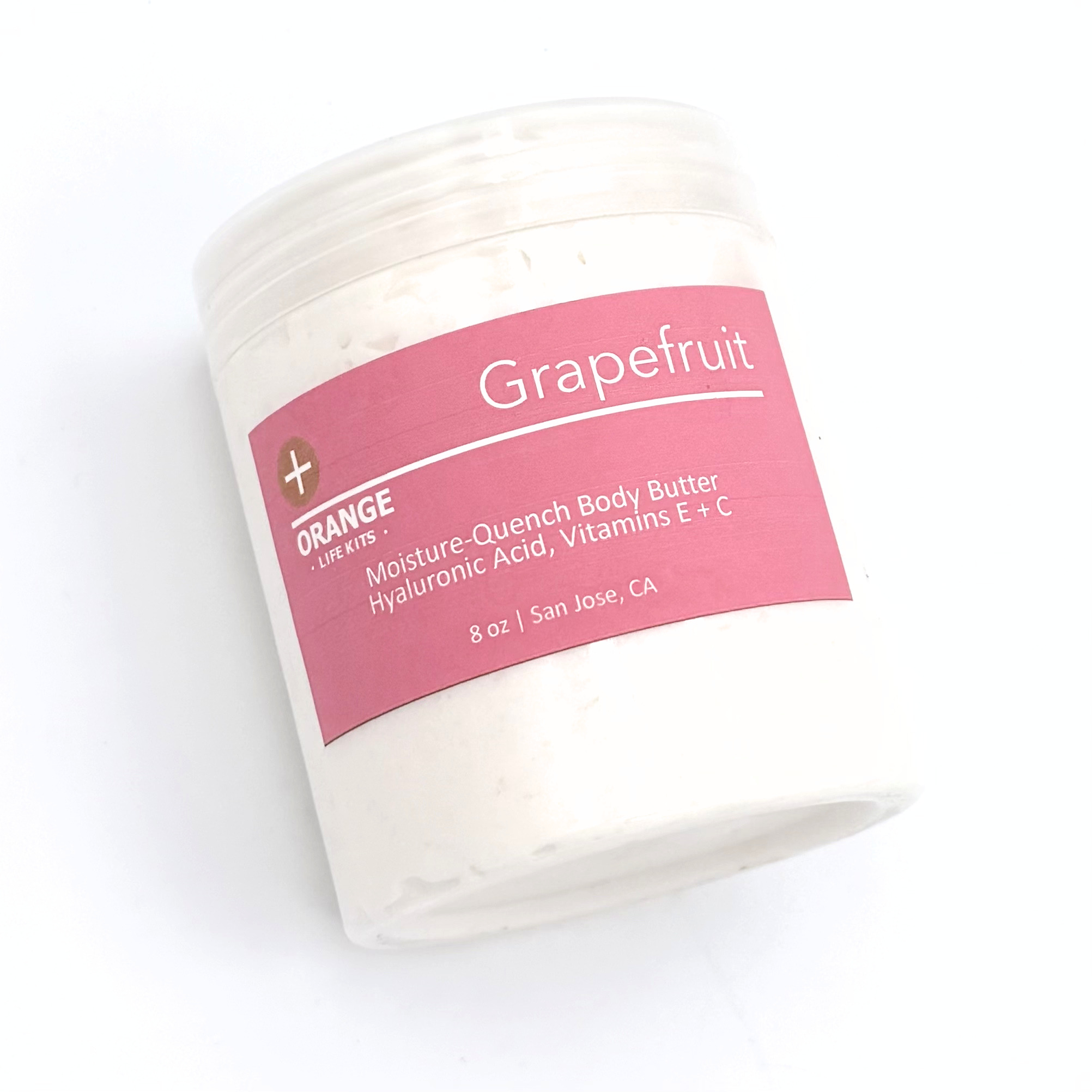 A close-up of a container of grapefruit scented body butter with a pink label.