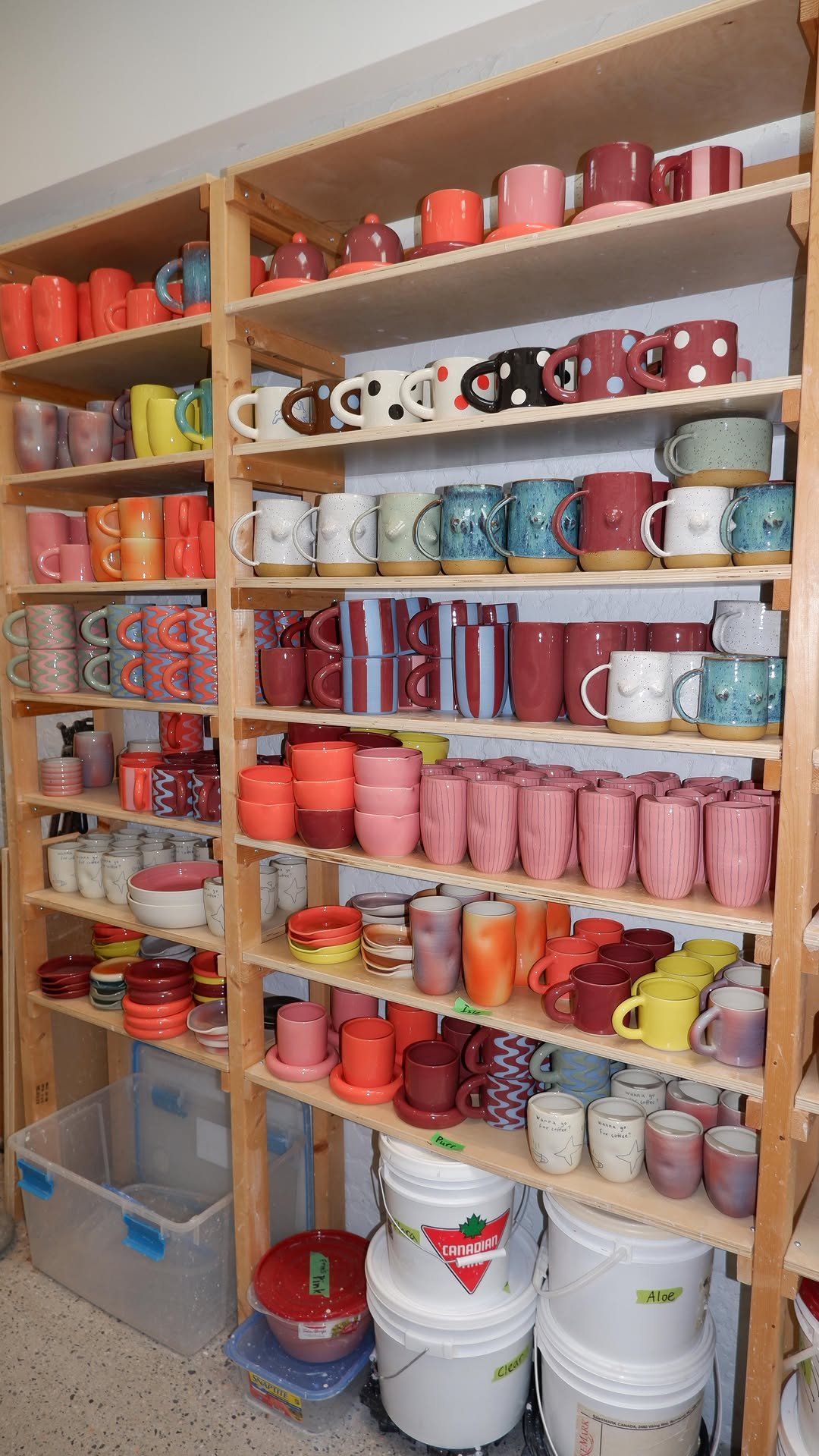 Amphora Ceramics.  A ceramic artist in Victoria, BC.  Shelves filled with colorful ceramic mugs, cups, and bowls arranged in rows.