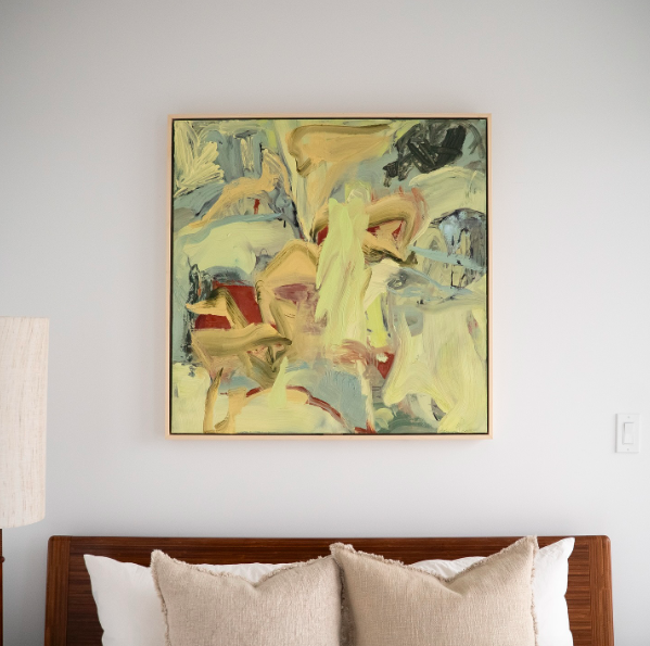  Robyn Jin, a painter and artist in Victoria, BC. Abstract painting with yellow, beige, black, red, and blue colors hanging above a bed with white pillows and a wooden headboard in a bedroom.