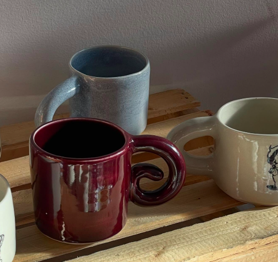 Slug Studios mugs.  A ceramic artist in Victoria, BC. Three ceramic mugs in different colors (blue, burgundy, cream) on a wooden surface.