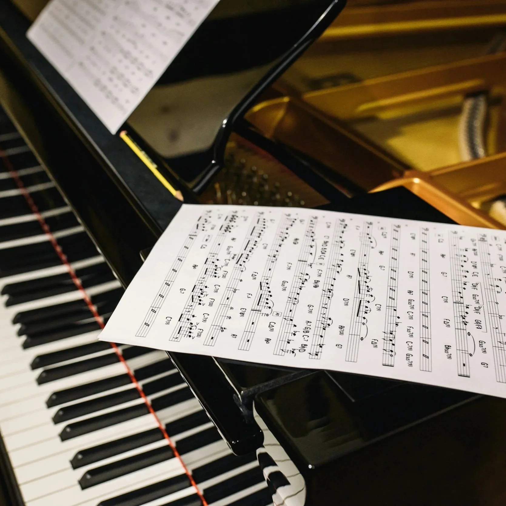 Close-up of a piano with a sheet of music and a mirror reflecting the sheet music.