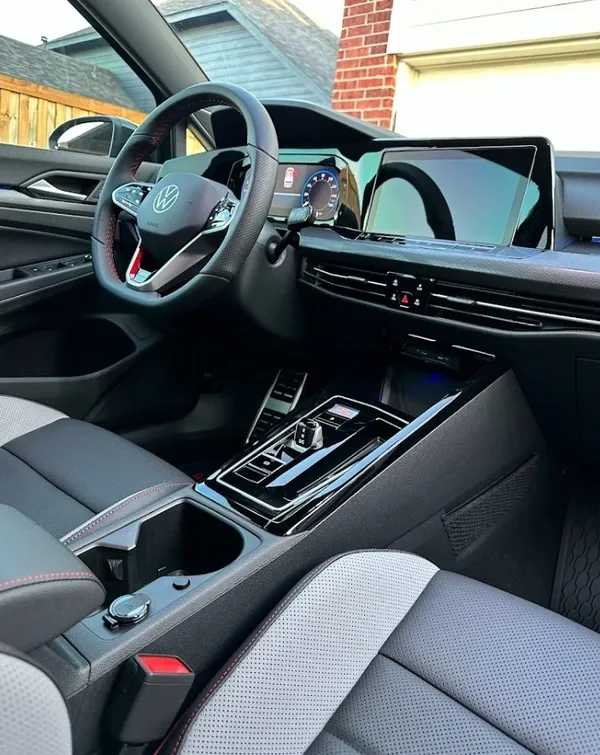 Interior of a modern Volkswagen car with a digital dashboard, steering wheel, and center console with gear controls and a large infotainment screen.