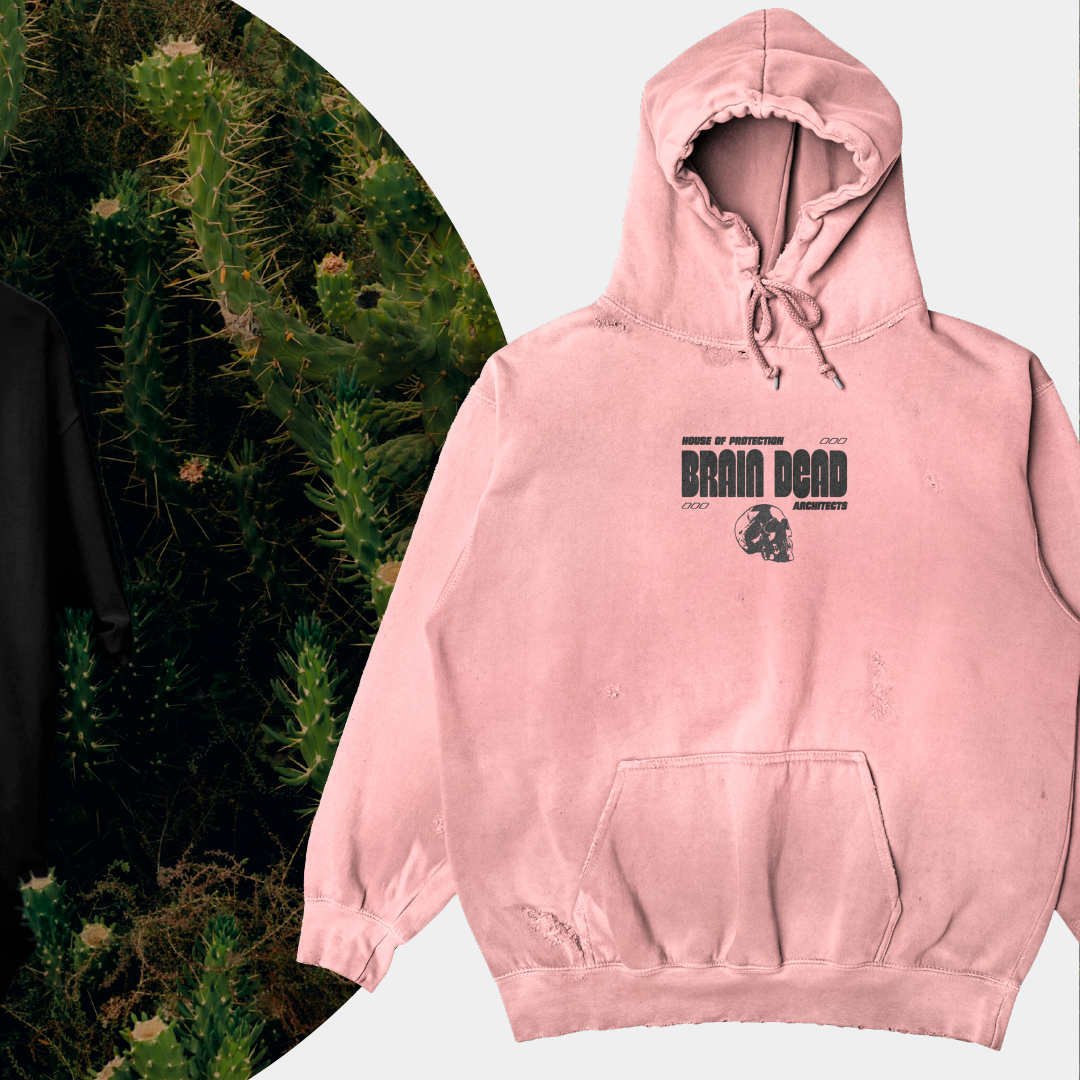 Un sweat à capuche rose délavé avec un logo noir 'BRAIN DEAD' et des textes 'HOUSE OF PROTECTION' et 'ARCHITECTS' sur la poitrine, et un dessin de skull. Fond partiellement composé de cactus verts.