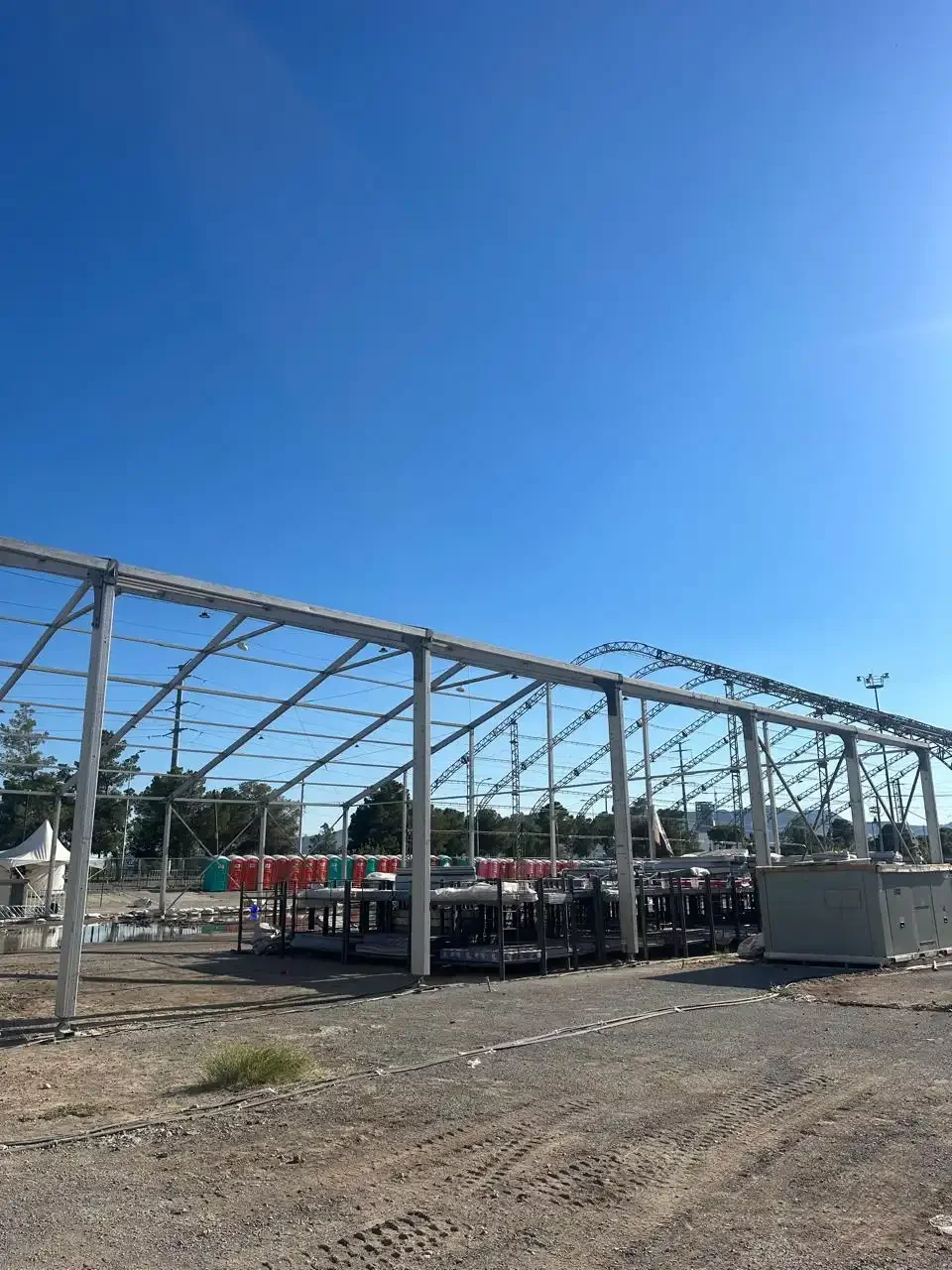 Estructura metálica en construcción con fondo de cielo despejado y maquinaria en un sitio de construcción.