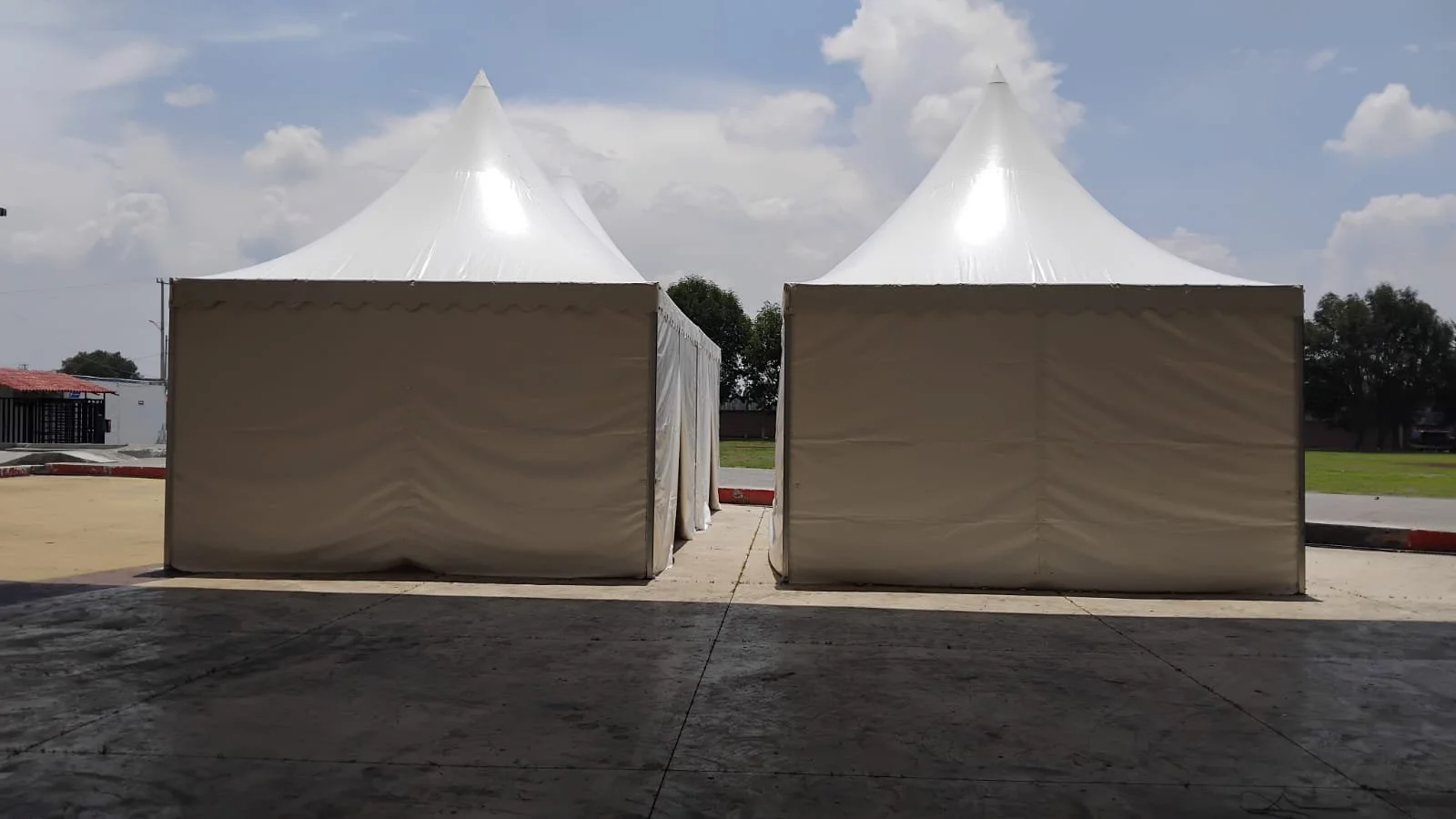 Dos carpas blancas en un espacio abierto con cielo parcialmente nublado.