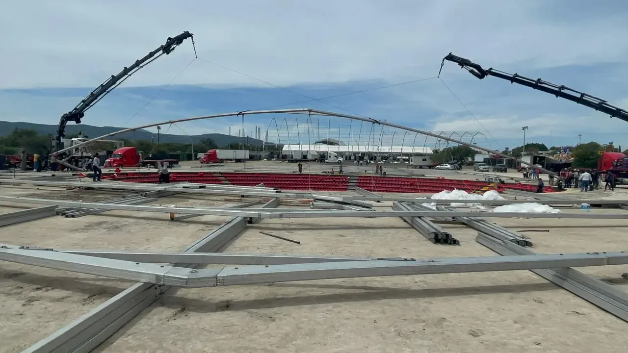 Proceso de montaje de una estructura metálica para una pista de hielo en un lugar abierto con maquinaria y trabajadores.